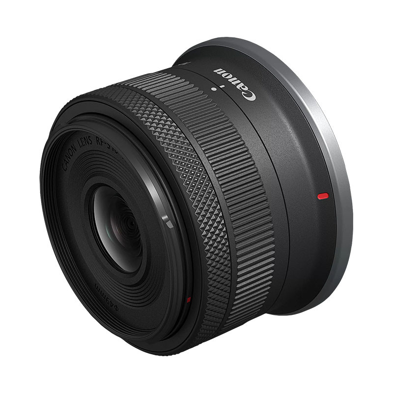 Un lente Canon RF negro con marcas plateadas y un punto rojo.