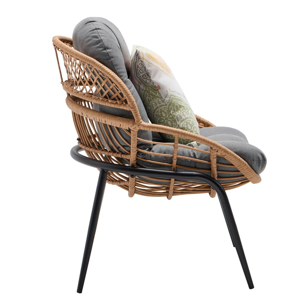 Poltrona in rattan marrone con cuscini grigi e un cuscino fantasia su sfondo bianco.