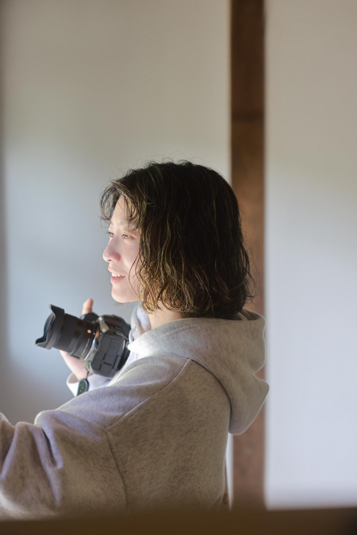 Eine Person mit einem Fotoapparat hält ihn in der Hand, schaut nach links.