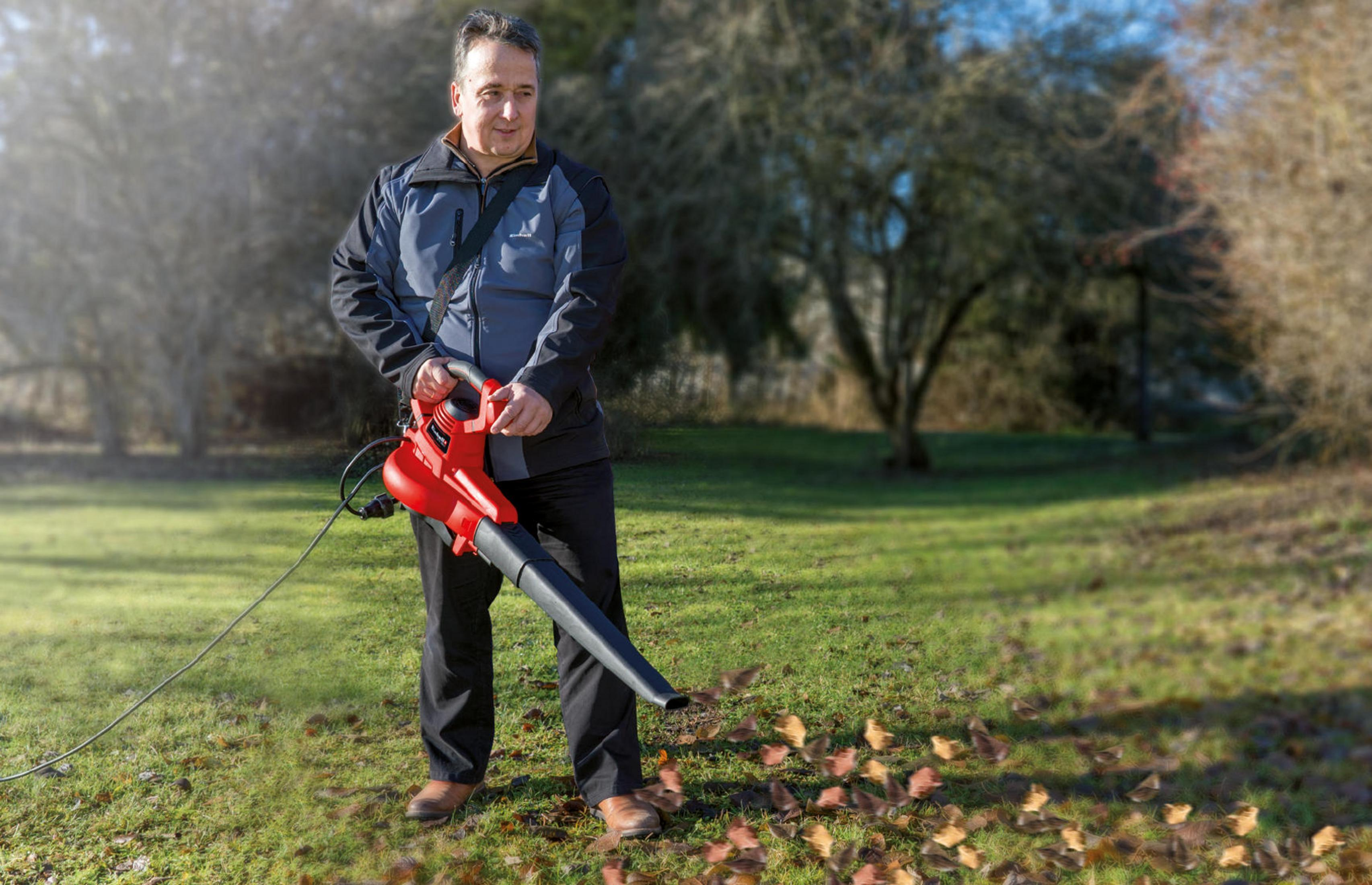 Hombre con soplador de hojas al aire libre, sobre césped con hojas.