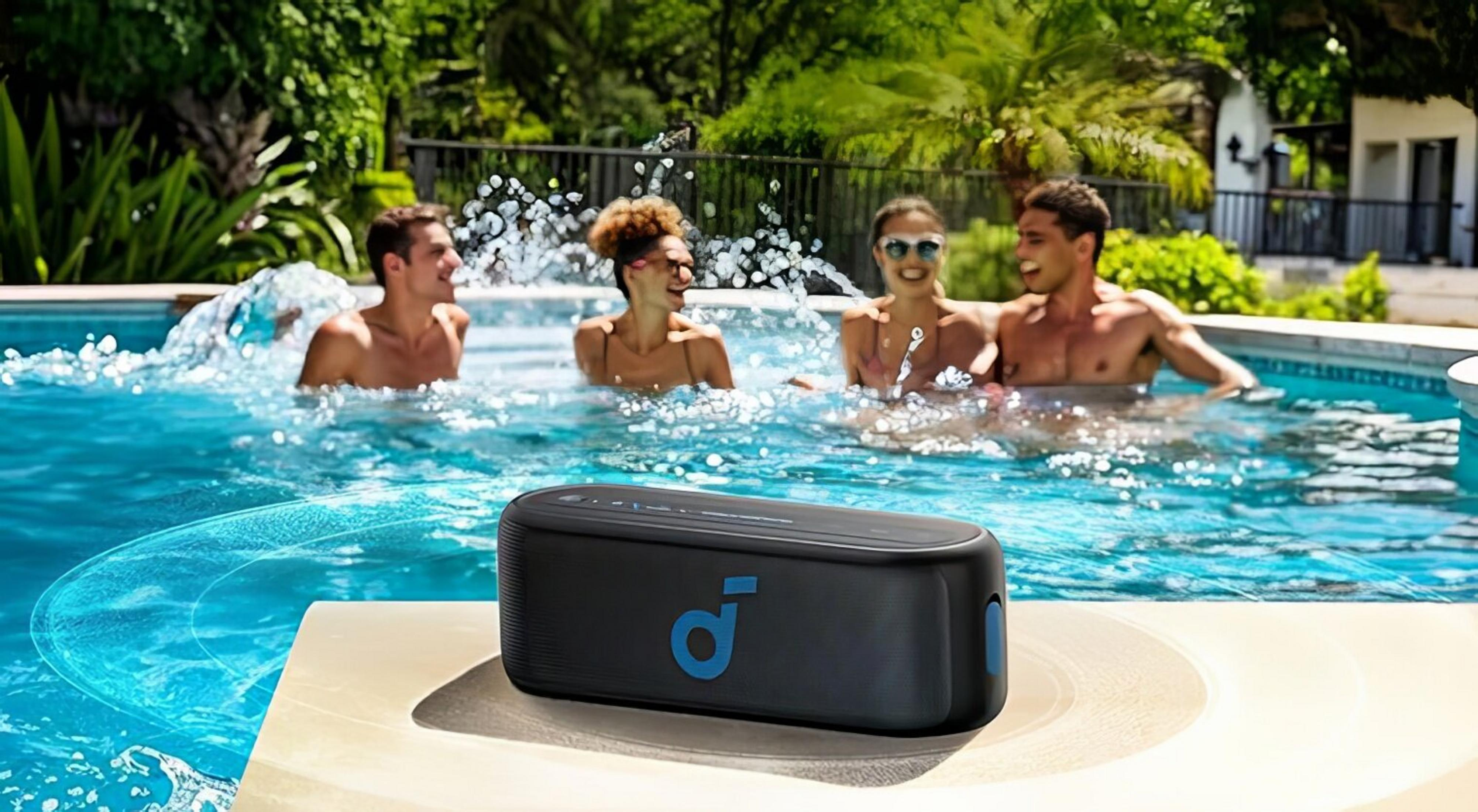 Un altoparlante nero sul bordo piscina, quattro persone sguazzano nell'acqua.