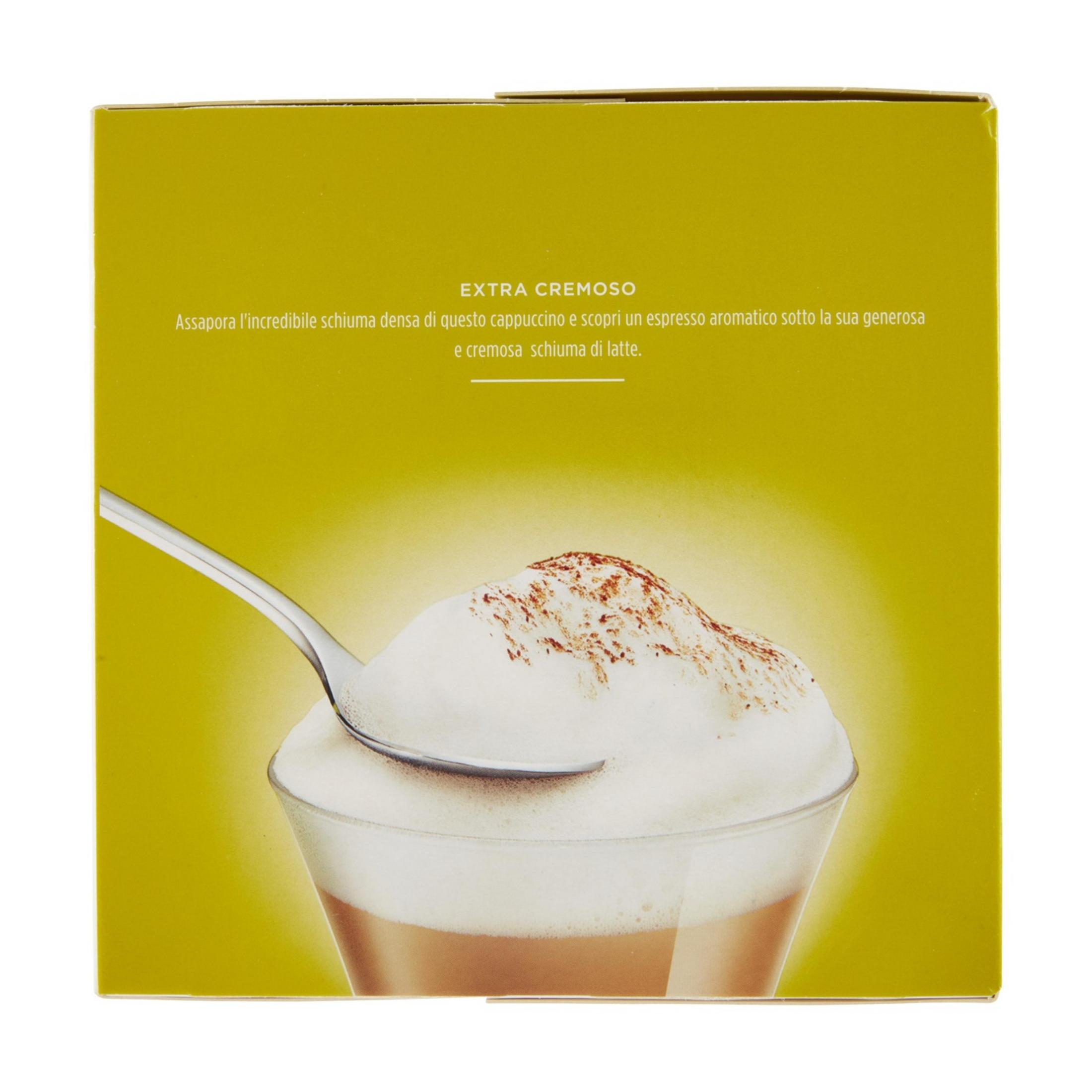 Un bicchiere di cappuccino con schiuma di latte e cacao, con un cucchiaio sopra.