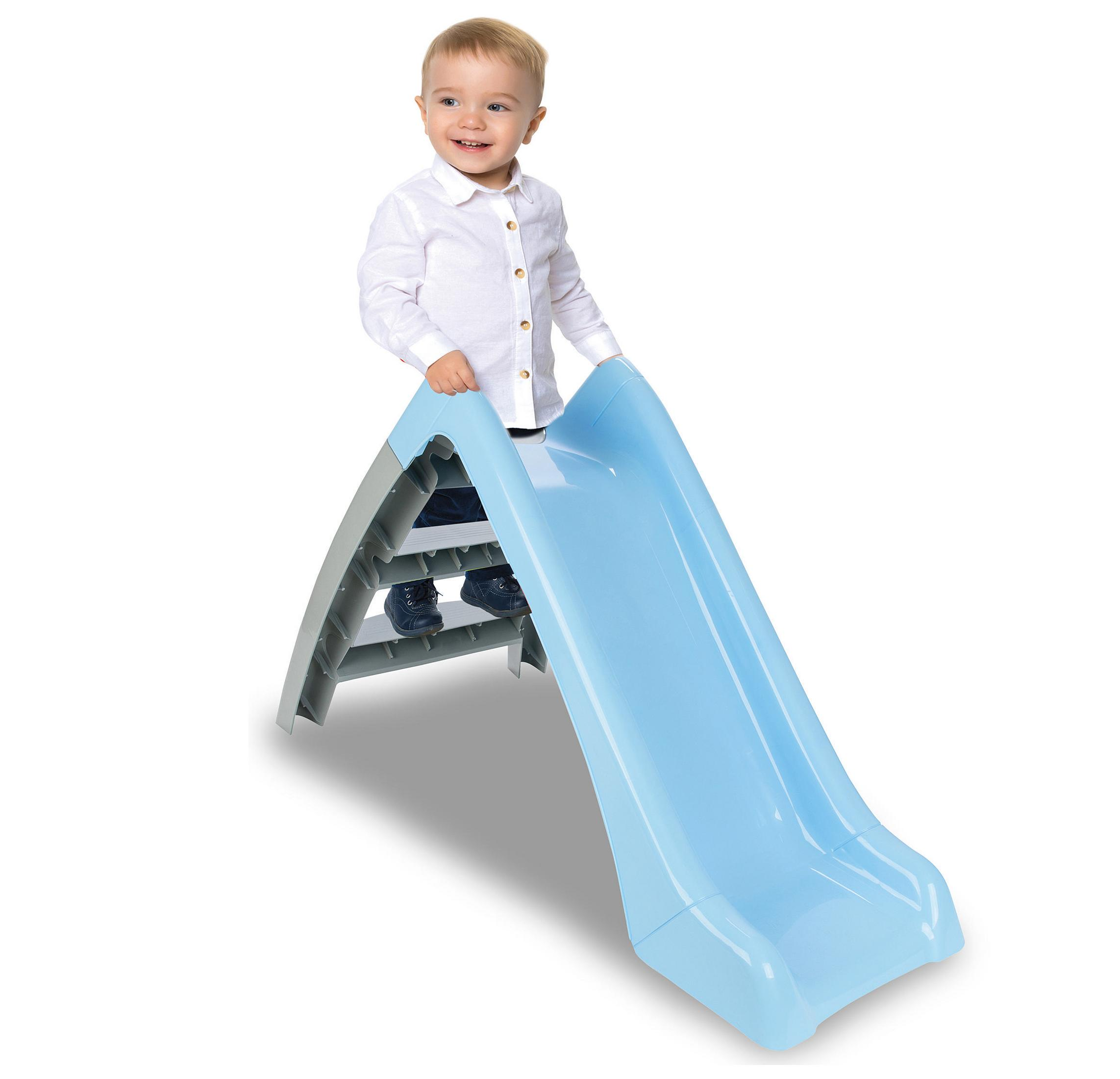 Ein Kleinkind in einem weißen Hemd steht auf einer blauen Rutsche.