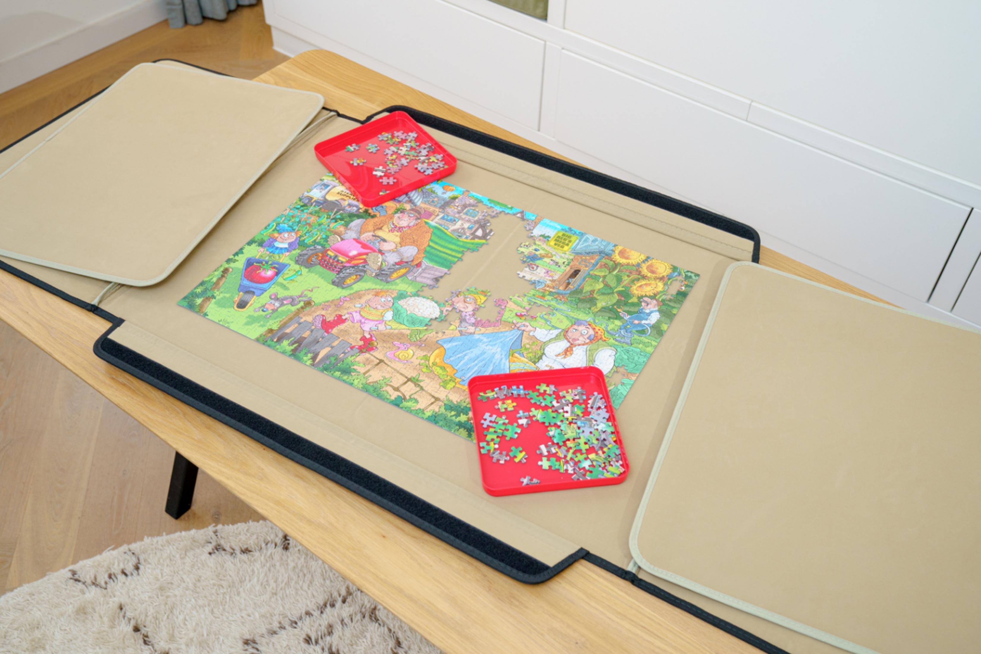 Un puzzle con scena rurale su tappetino marrone, con due vaschette rosse di pezzi.