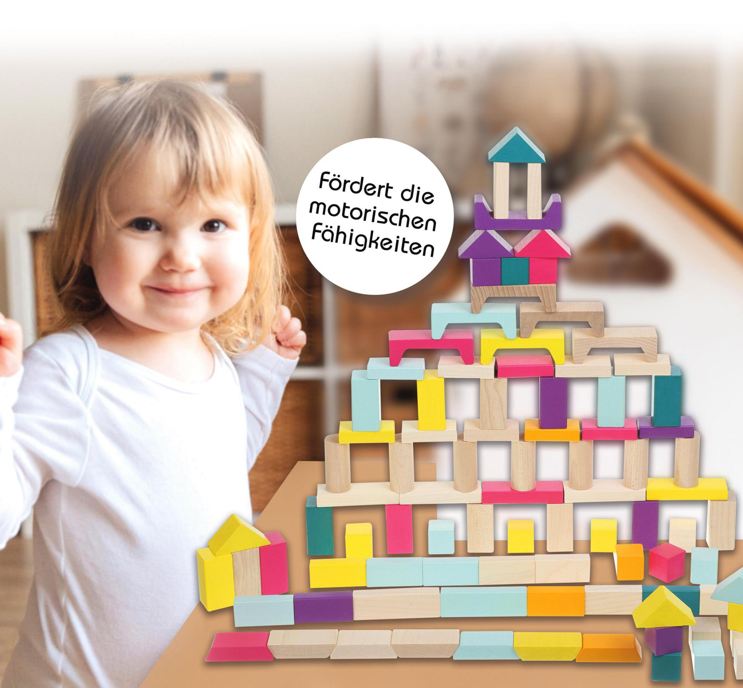 Ein lächelndes kleines Kind mit einem Turm aus bunten Holzbausteinen.