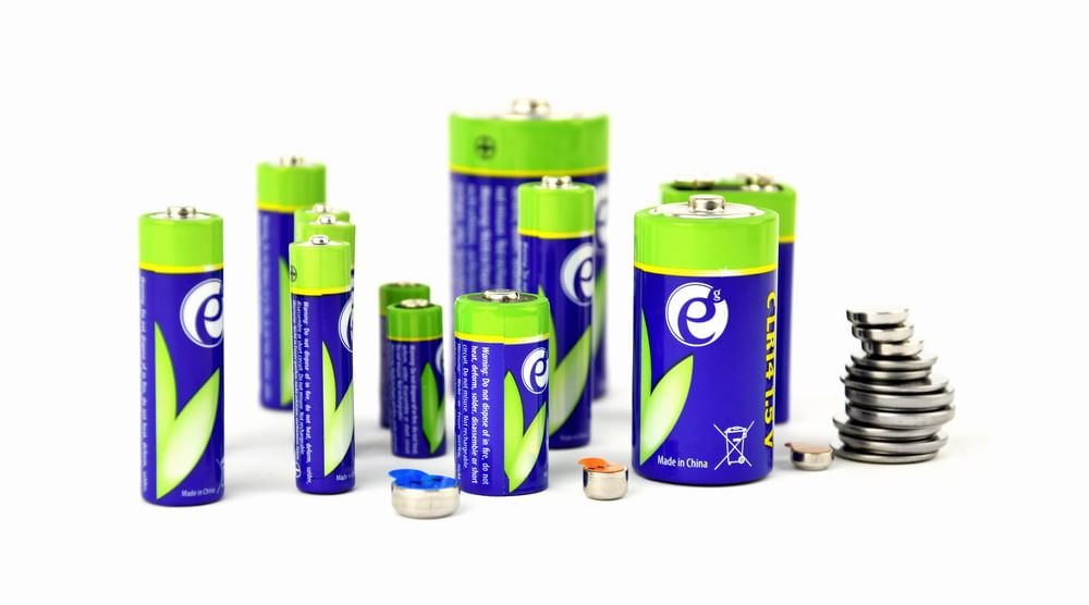 Una collezione di batterie alcaline e batterie a bottone su sfondo bianco.