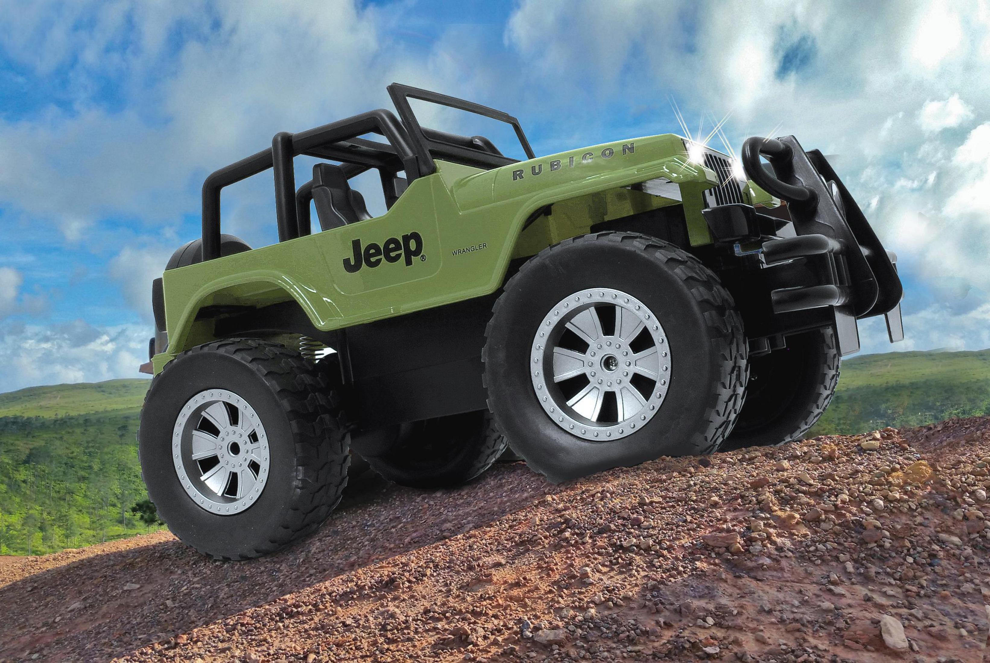 Grüner Jeep Rubicon mit großen Reifen auf felsigem Untergrund unter blauem Himmel.