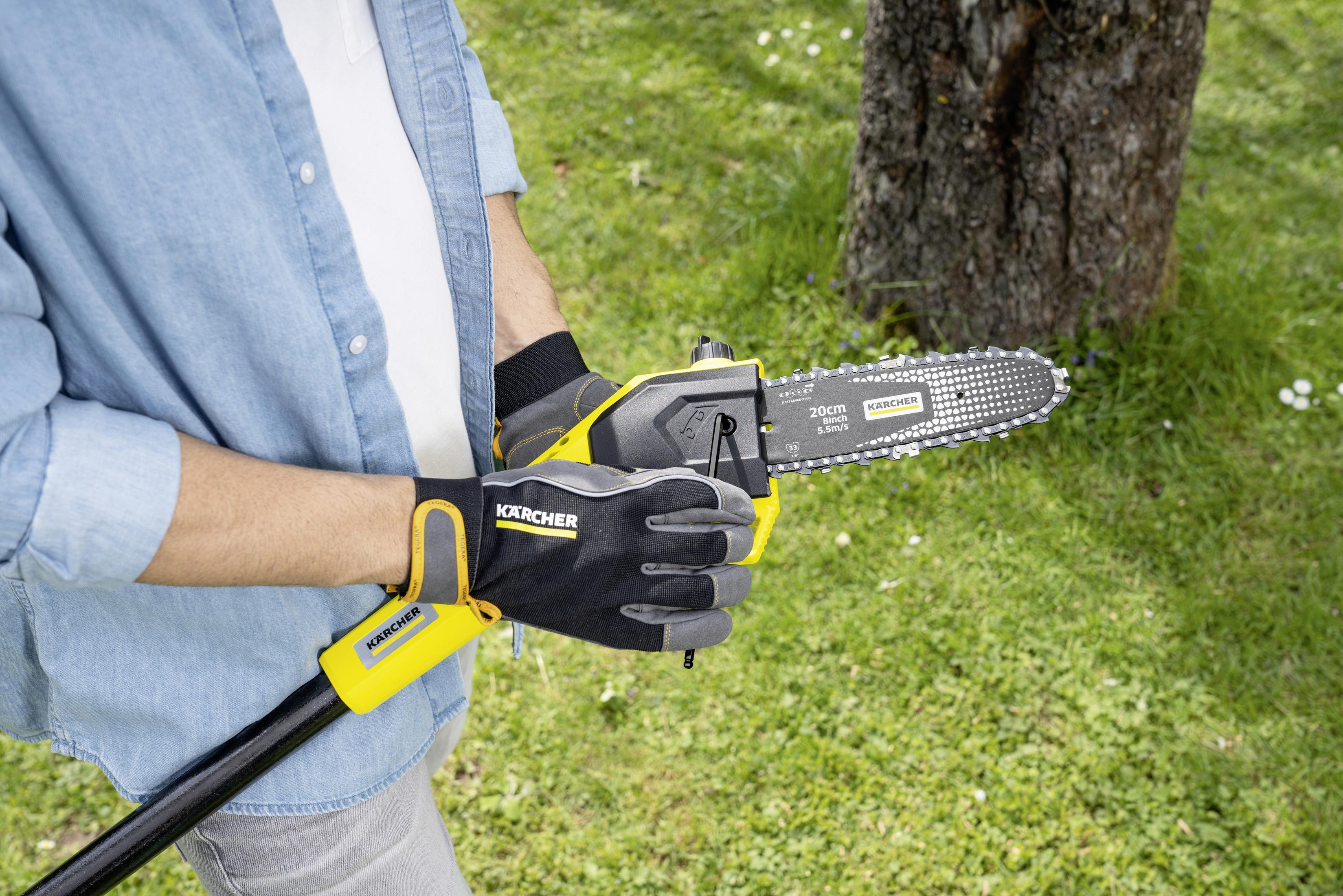 Person in Jeanshemd hält Kettensäge mit gelbem Griff im Garten.