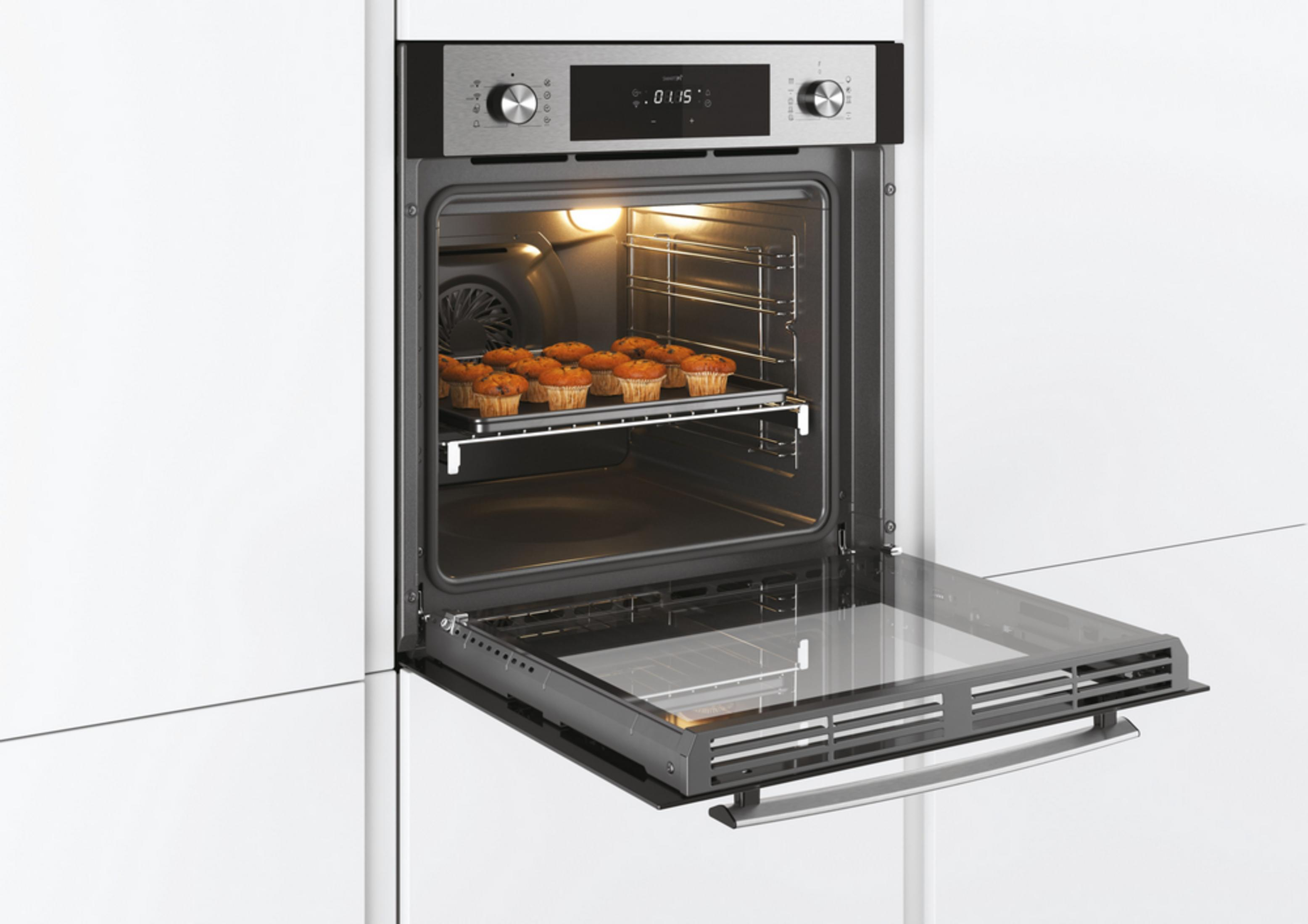 Un forno da incasso aperto con una teglia di muffin e interno illuminato.