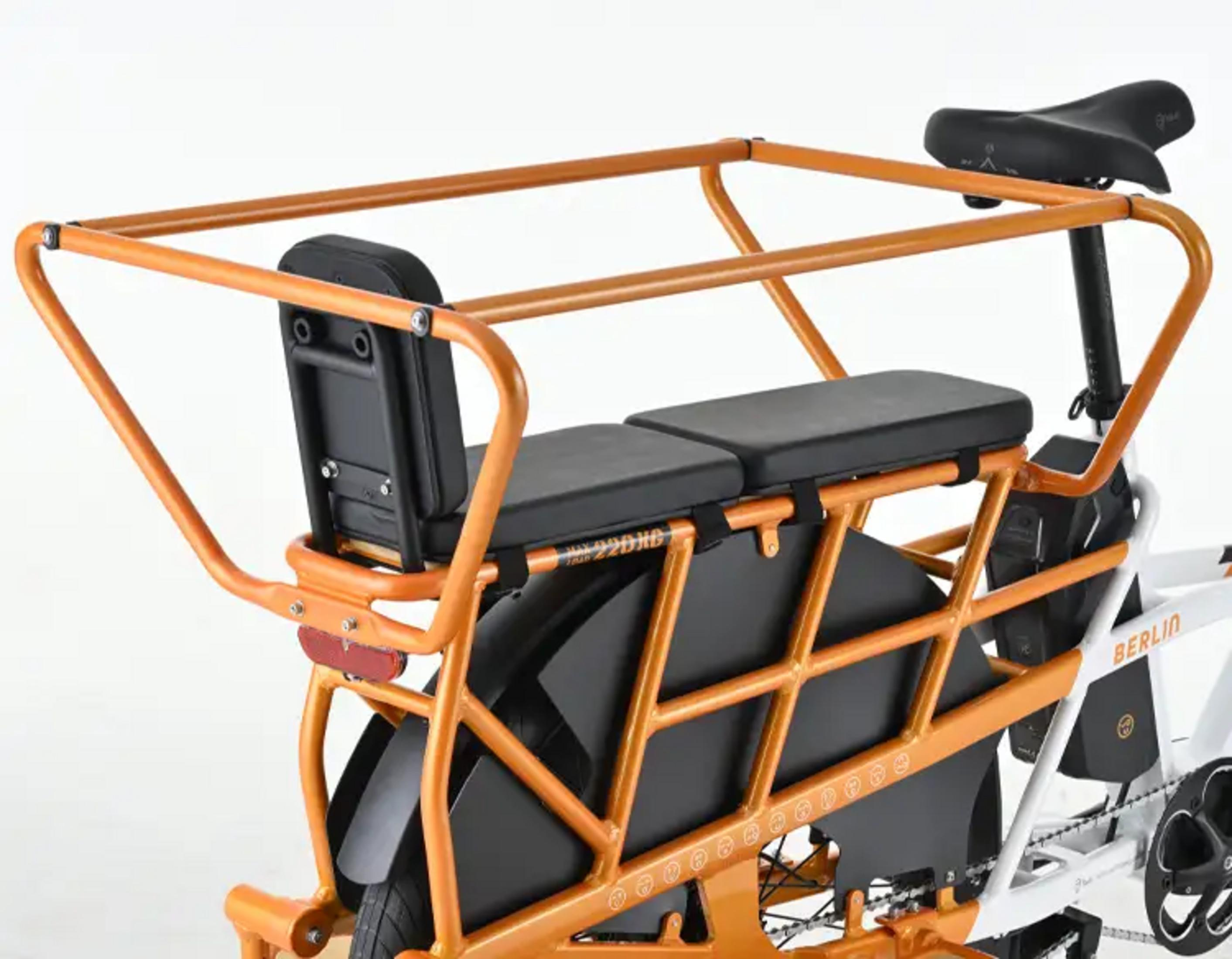 Bici cargo arancione con due sedili posteriori e portapacchi.