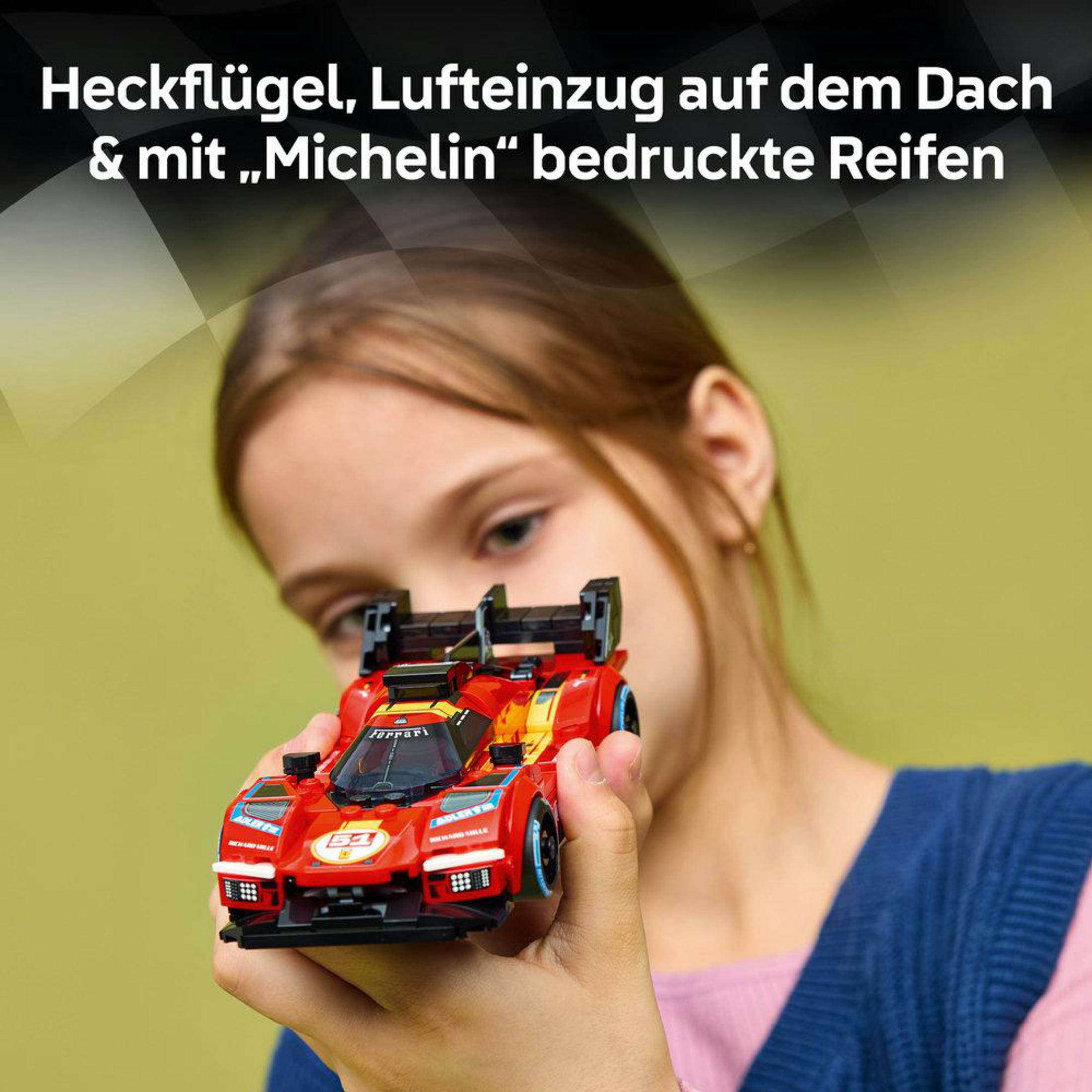 Bir çocuk kanatlı ve Michelin lastikli kırmızı bir Ferrari yarış arabası tutuyor.