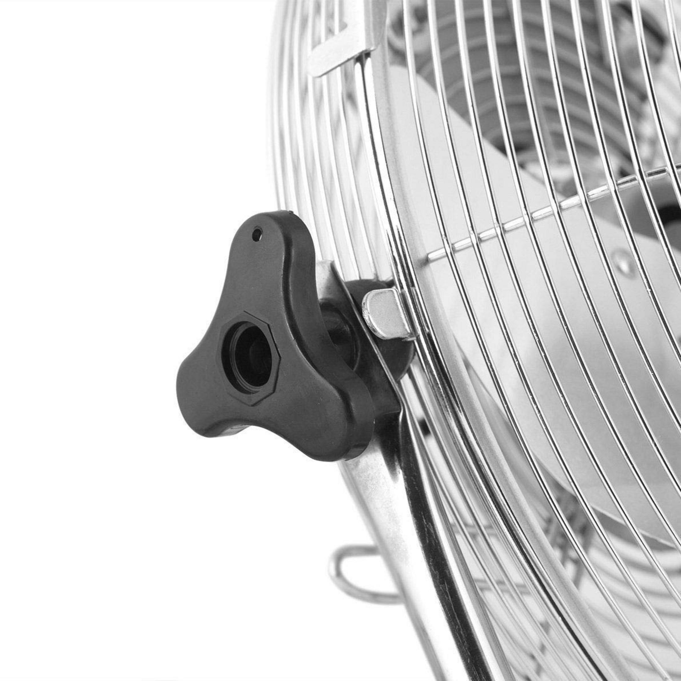 Primer plano de un pomo de ajuste negro en una rejilla de ventilador plateada.