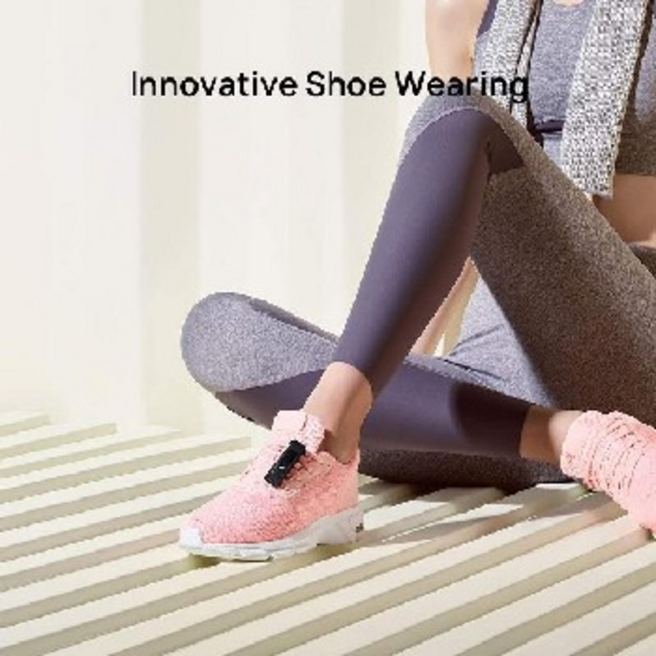 Eine Person mit rosafarbenen Schuhen und lila Leggings sitzt auf einer gestreiften Oberfläche.