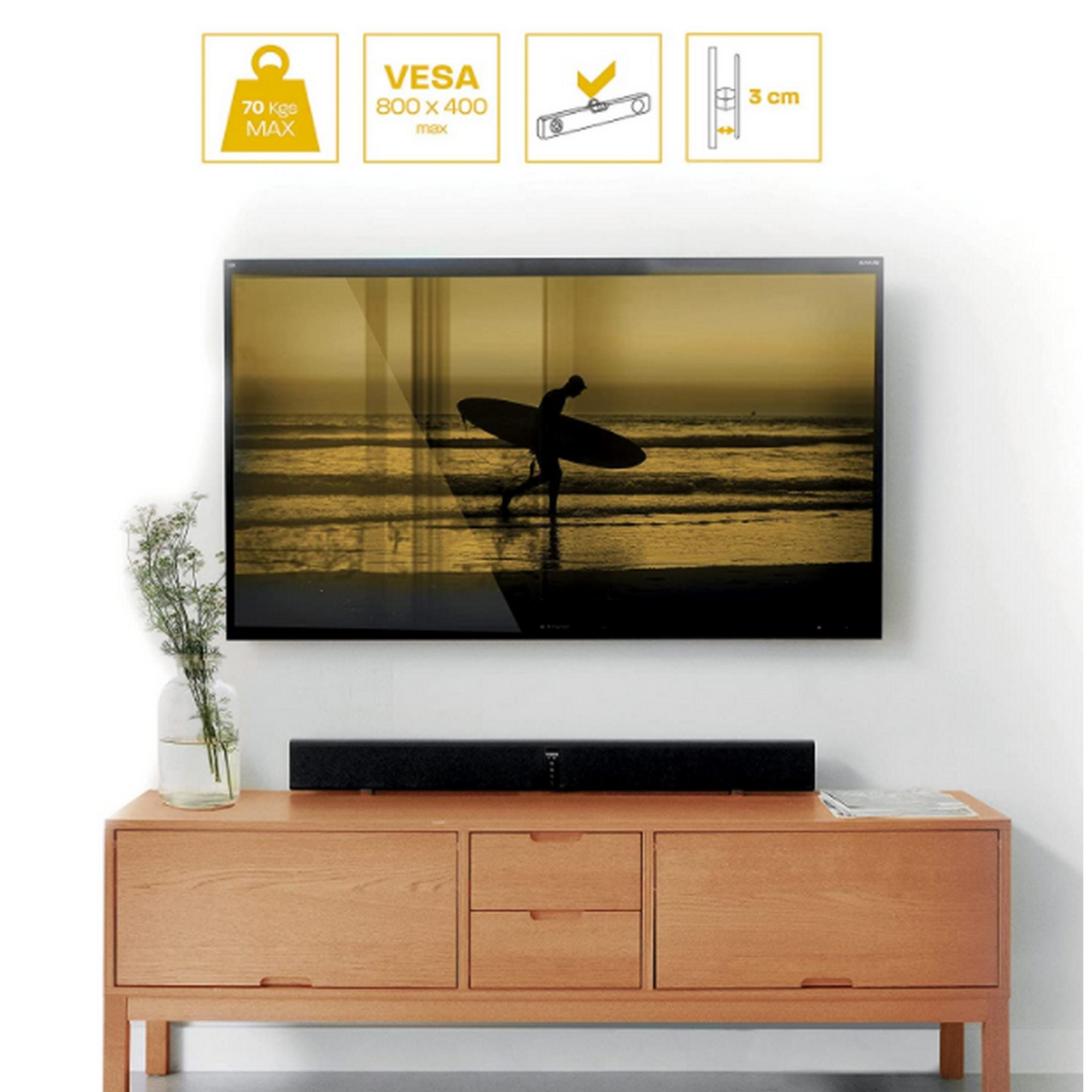 Un televisor con imagen de surfista sobre mueble de madera con barra de sonido.