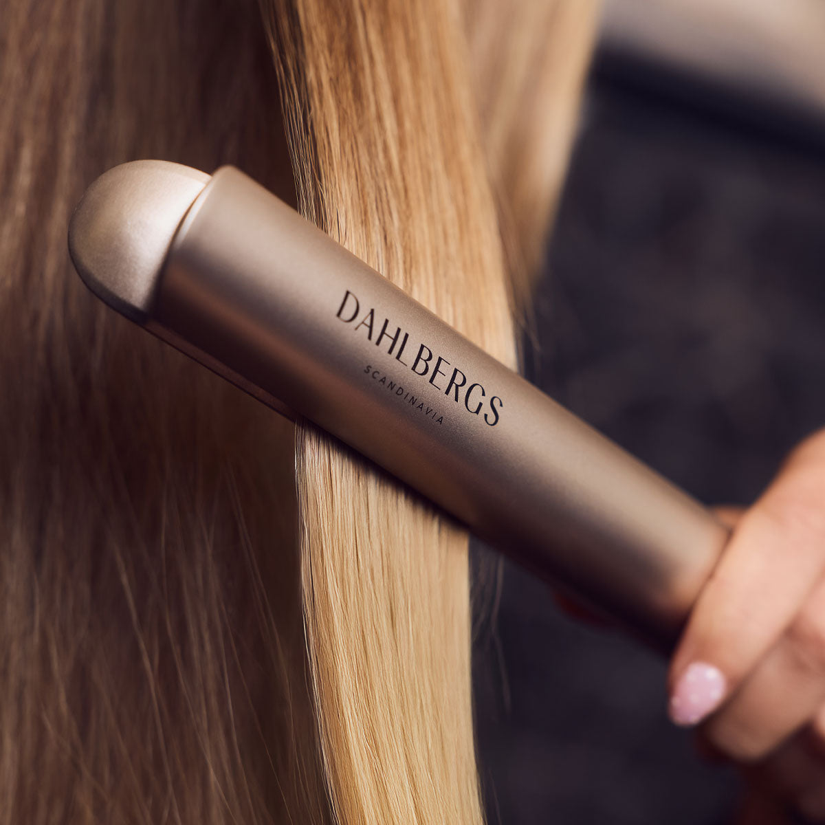 Una plancha dorada para el cabello alisa el pelo rubio.
