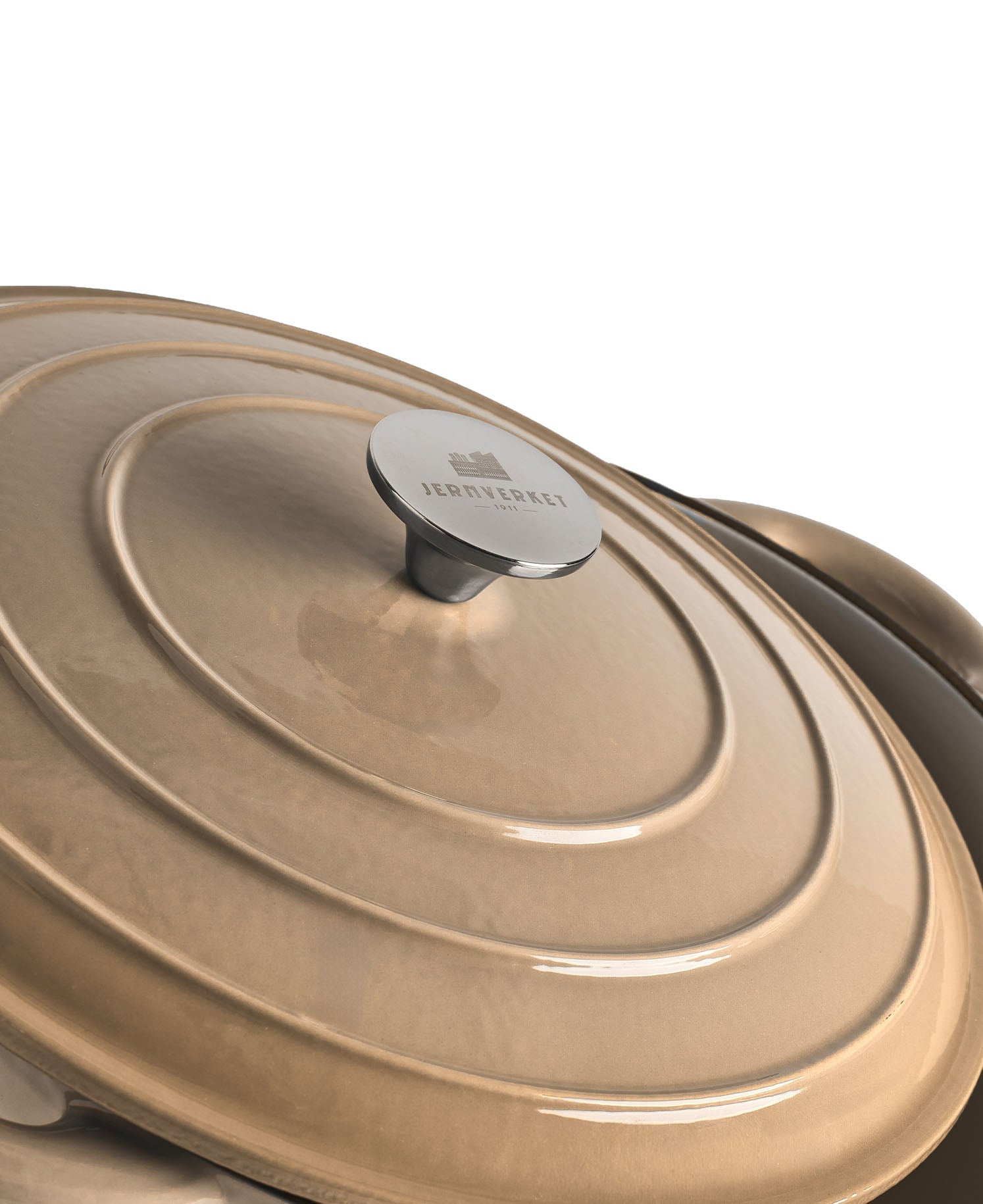 Una tapa de olla beige con anillos concéntricos y un asa plateada.
