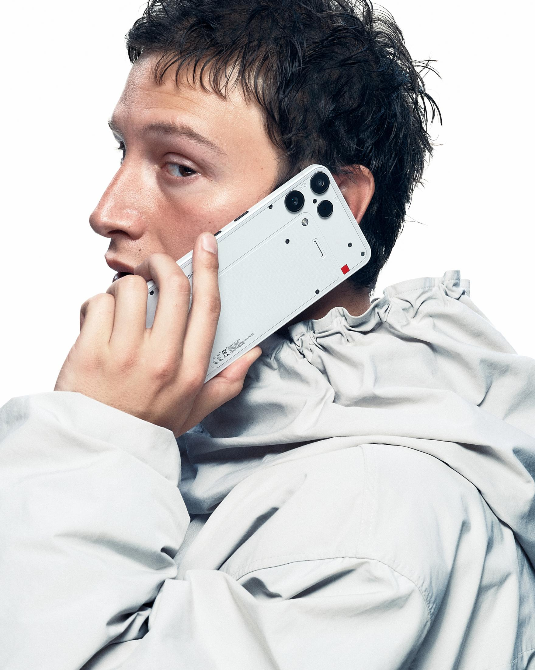 Mann mit Handy am Ohr, trägt eine graue Jacke.
