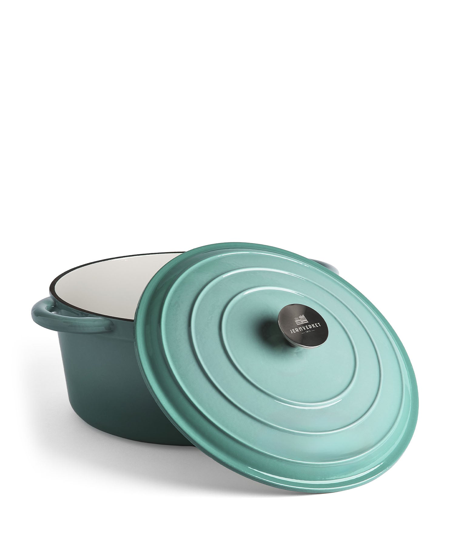 Una olla de hierro fundido esmaltada turquesa con tapa sobre fondo blanco.