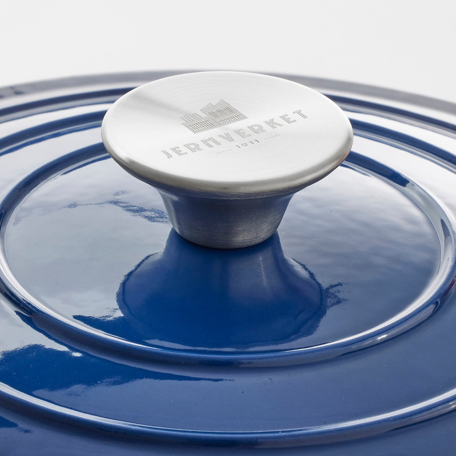 Una olla azul con asa plateada, grabada con logo y el año 1911.