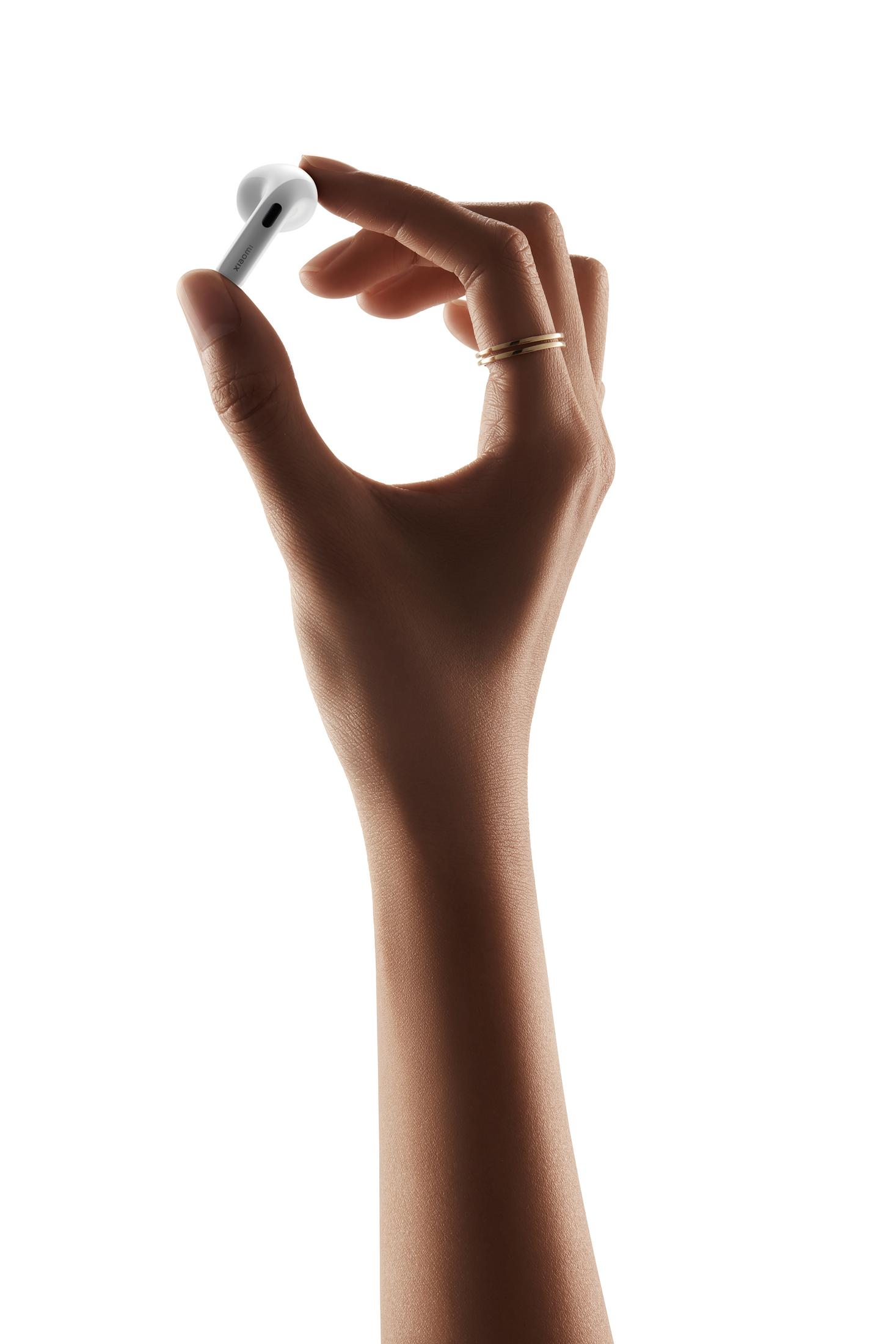 Eine Hand hält einen weißen Xiaomi-Kopfhörer mit zwei Ringen am Finger.