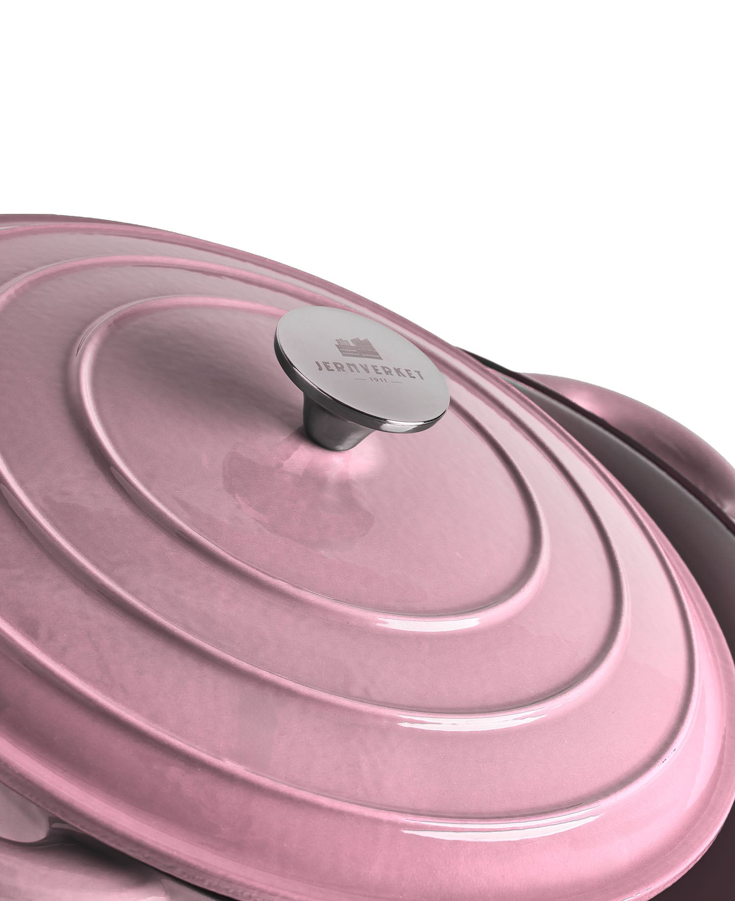 Una tapa de olla de hierro fundido rosa con círculos concéntricos y un asa plateada.
