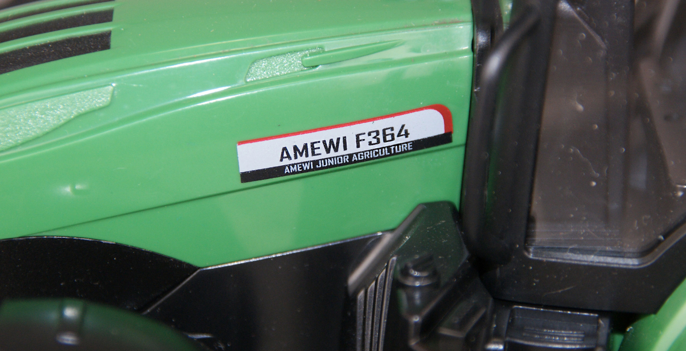 Grüner Spielzeugtraktor mit Aufkleber: AMEWI F364, AMEWI JUNIOR AGRICULTURE.