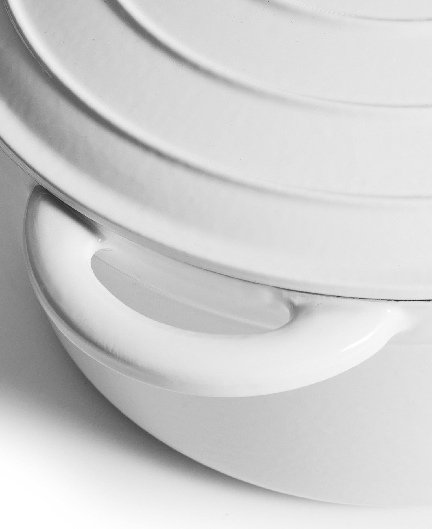 Primer plano de una olla blanca con asa y tapa acanalada.