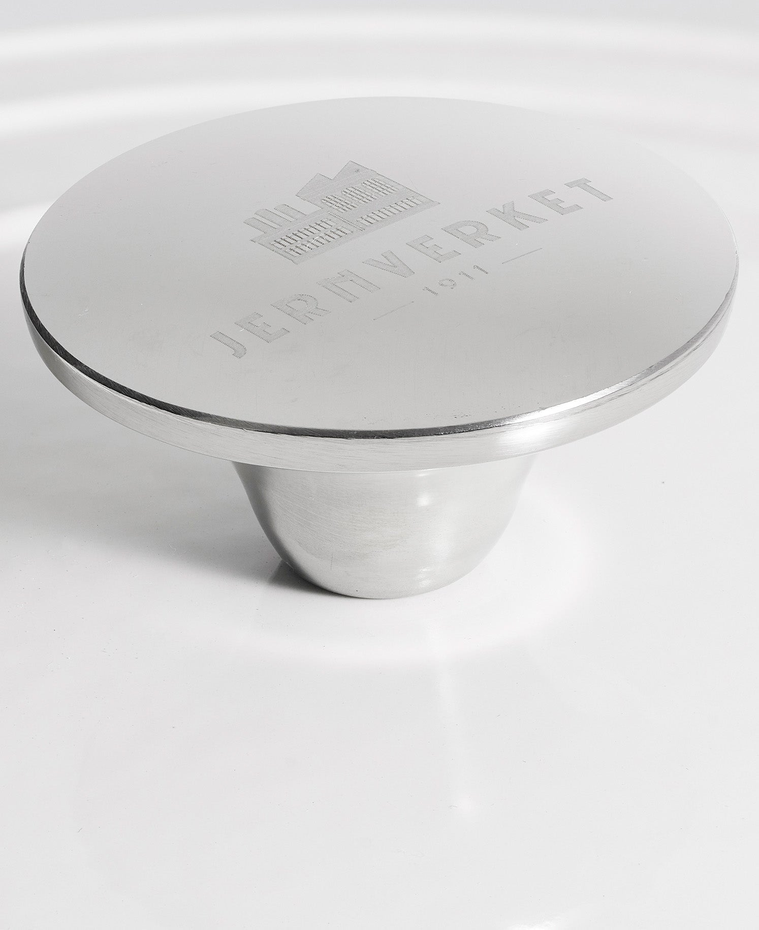 Mango de metal plateado con grabado "JERNVERKET 1911" sobre fondo blanco.