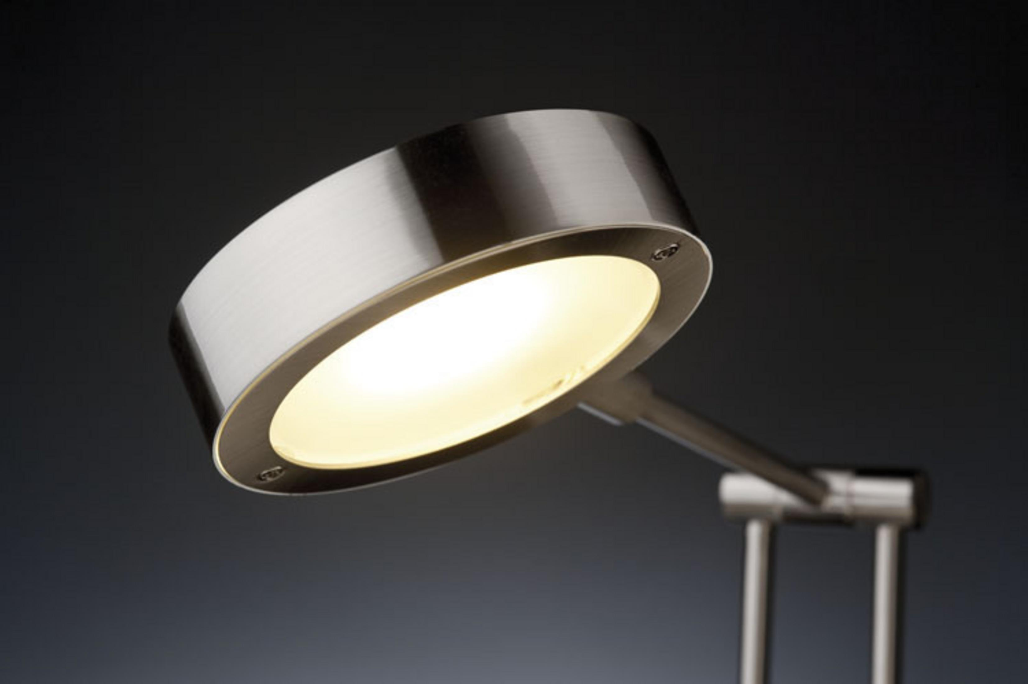 Una moderna lampada in metallo spazzolato con luce calda su sfondo scuro.