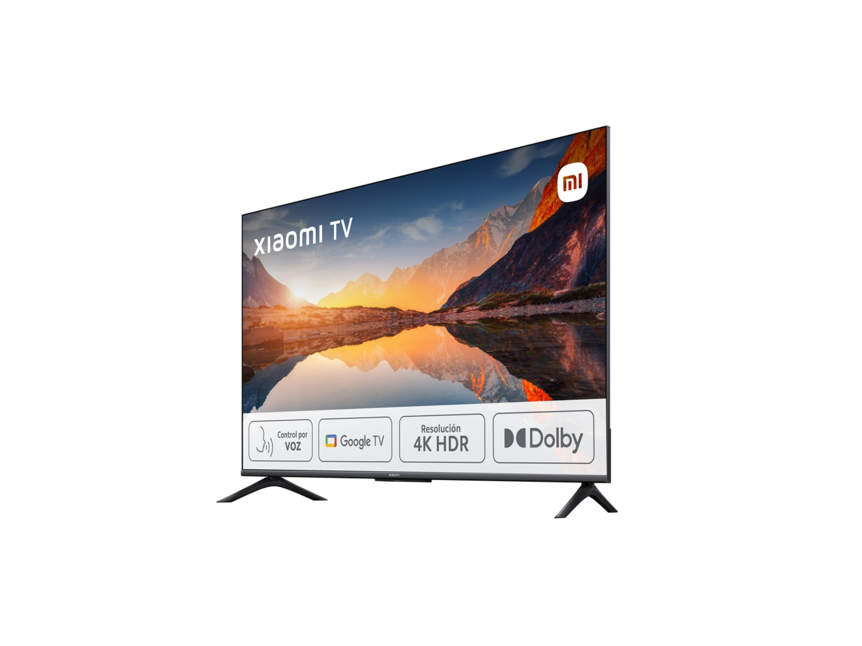 Una TV Xiaomi mostra un paesaggio montano con riflessi del tramonto su un lago. Funzionalità: controllo vocale, Google TV, 4K HDR, Dolby.