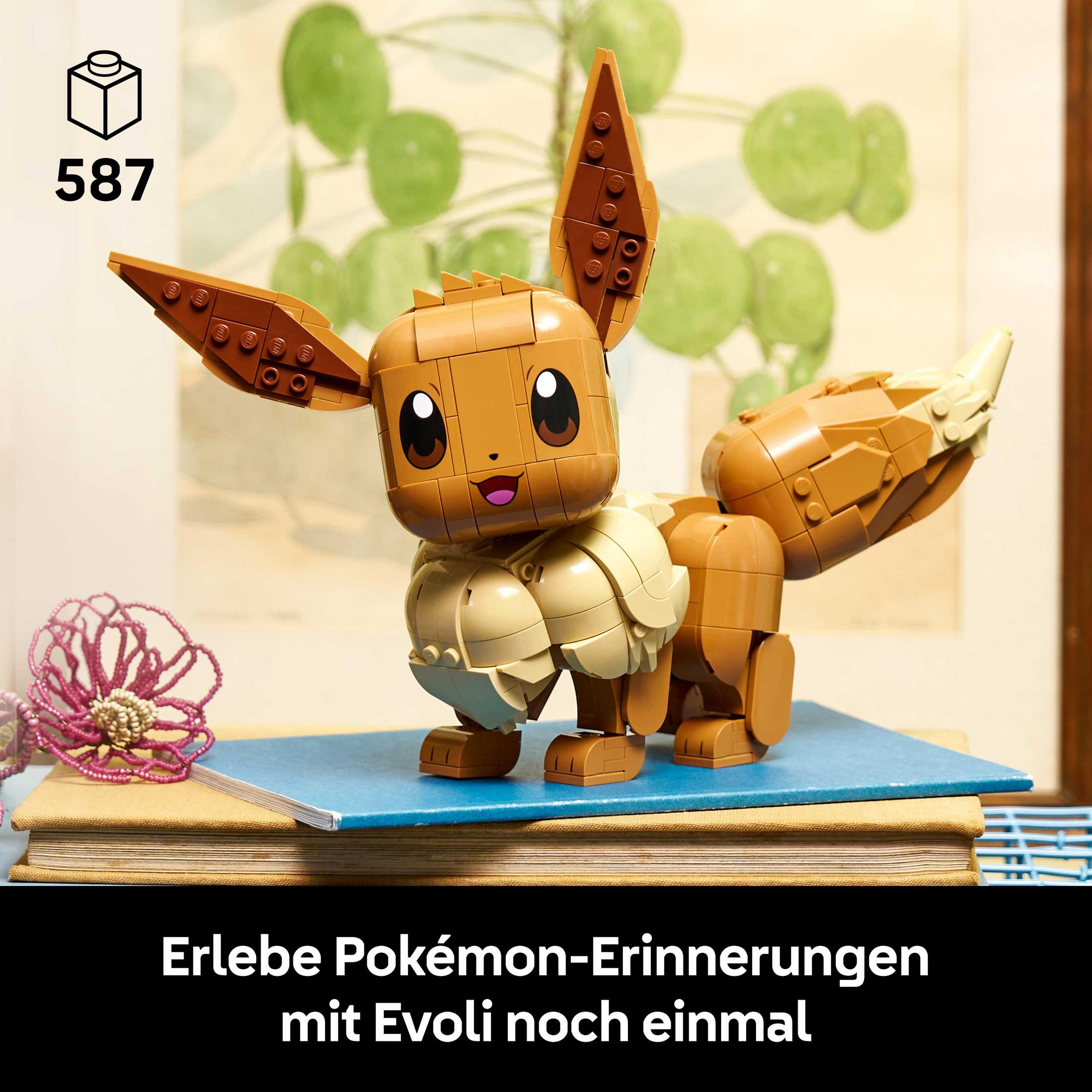 Un Eevee de Lego marrón está sobre libros. Una planta al fondo.