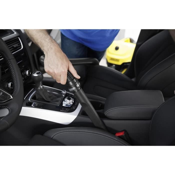 Una mano usa un aspirapolvere per pulire la console centrale di un'auto.