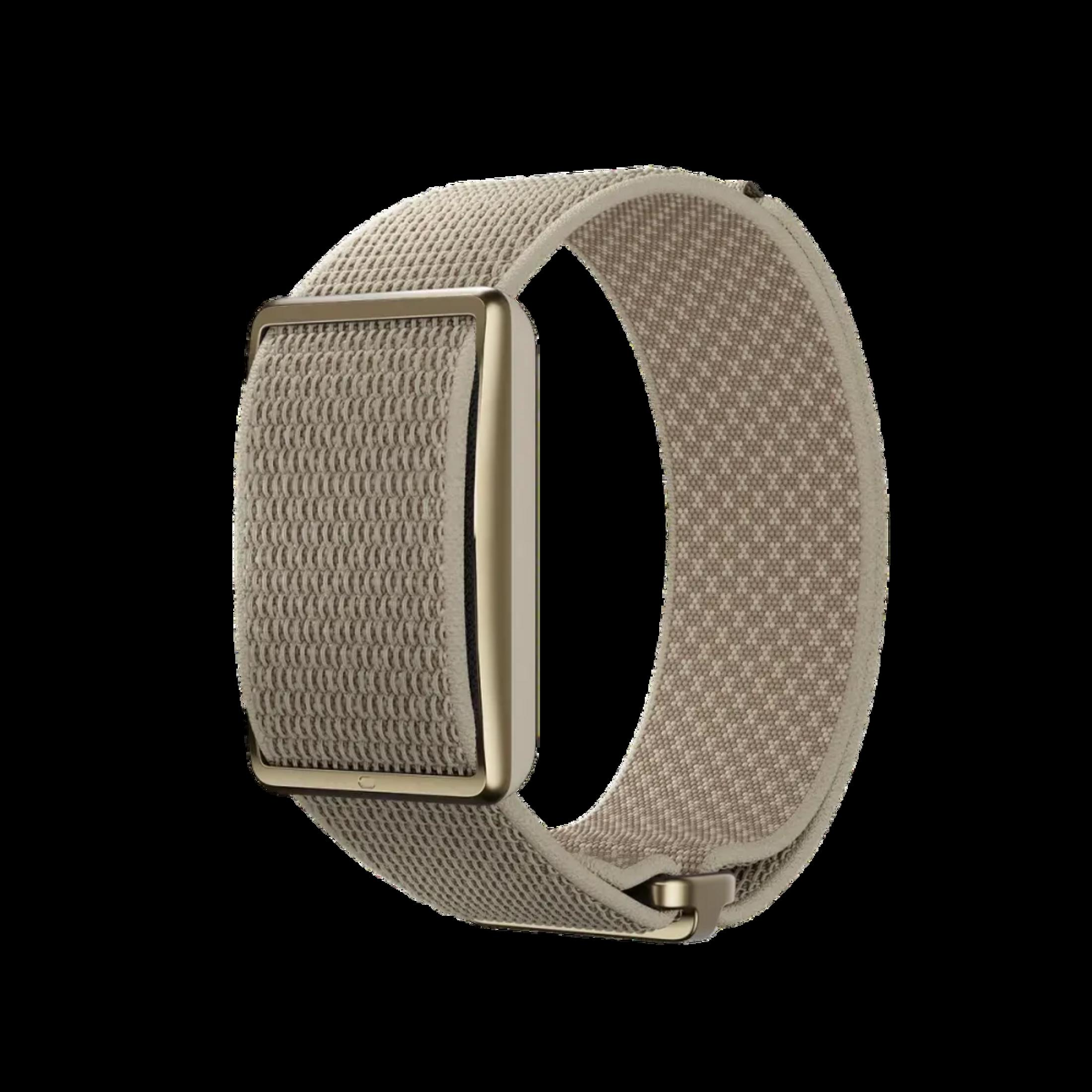 Una pulsera de tela beige con cierre dorado, aislada sobre fondo negro.