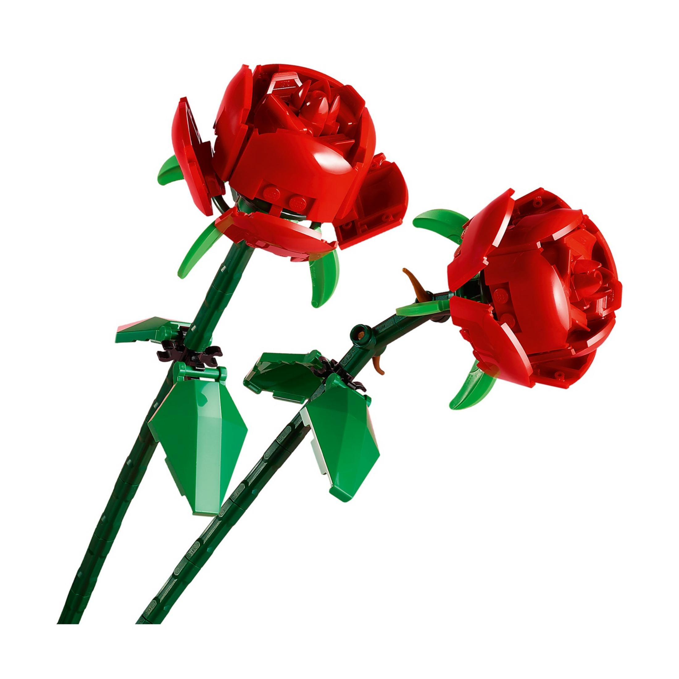 Due rose rosse Lego con steli e foglie verdi su sfondo bianco.