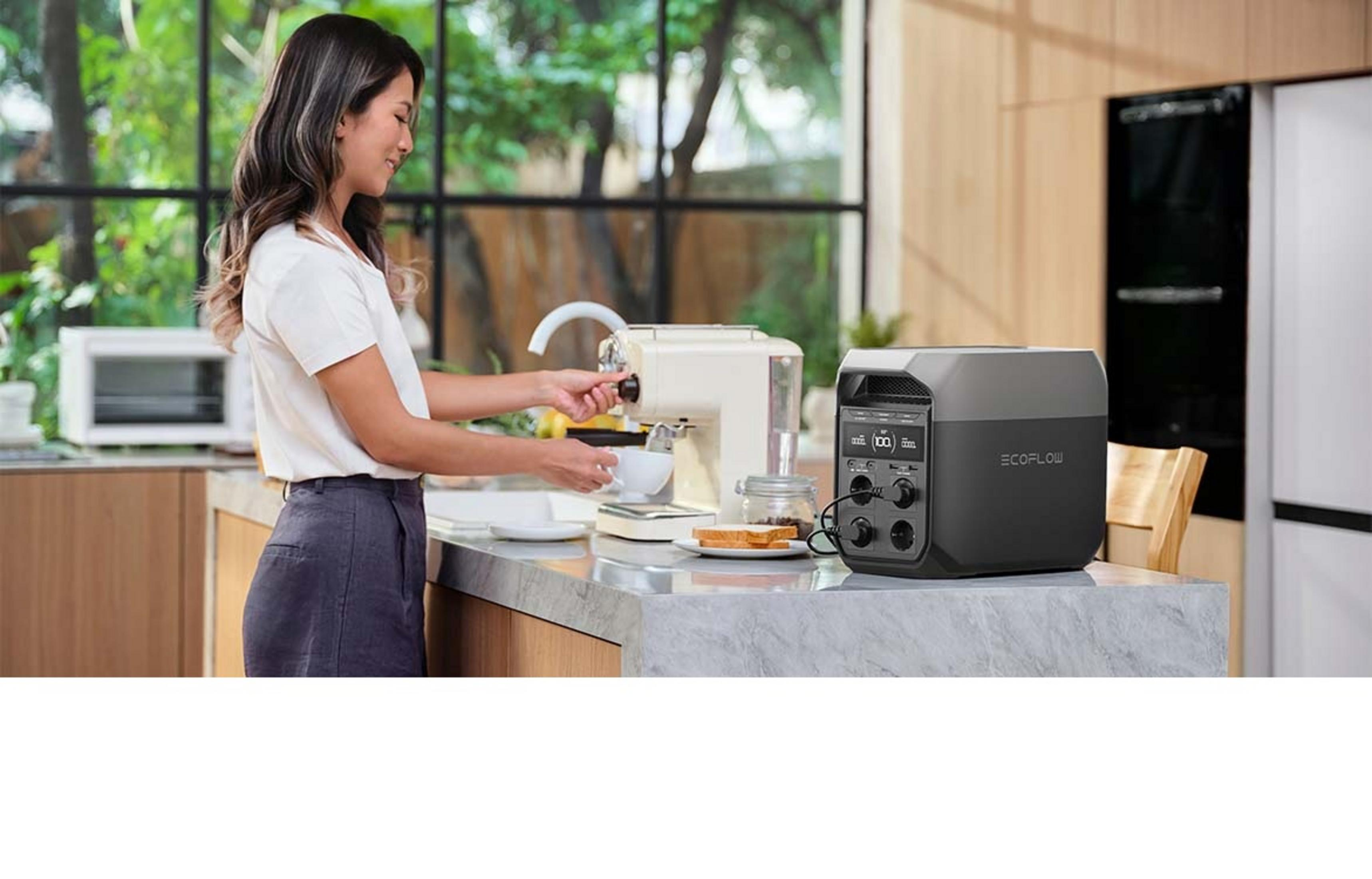 Frau macht Kaffee neben einer tragbaren Powerstation mit Toast und einem Glas Kaffeebohnen.