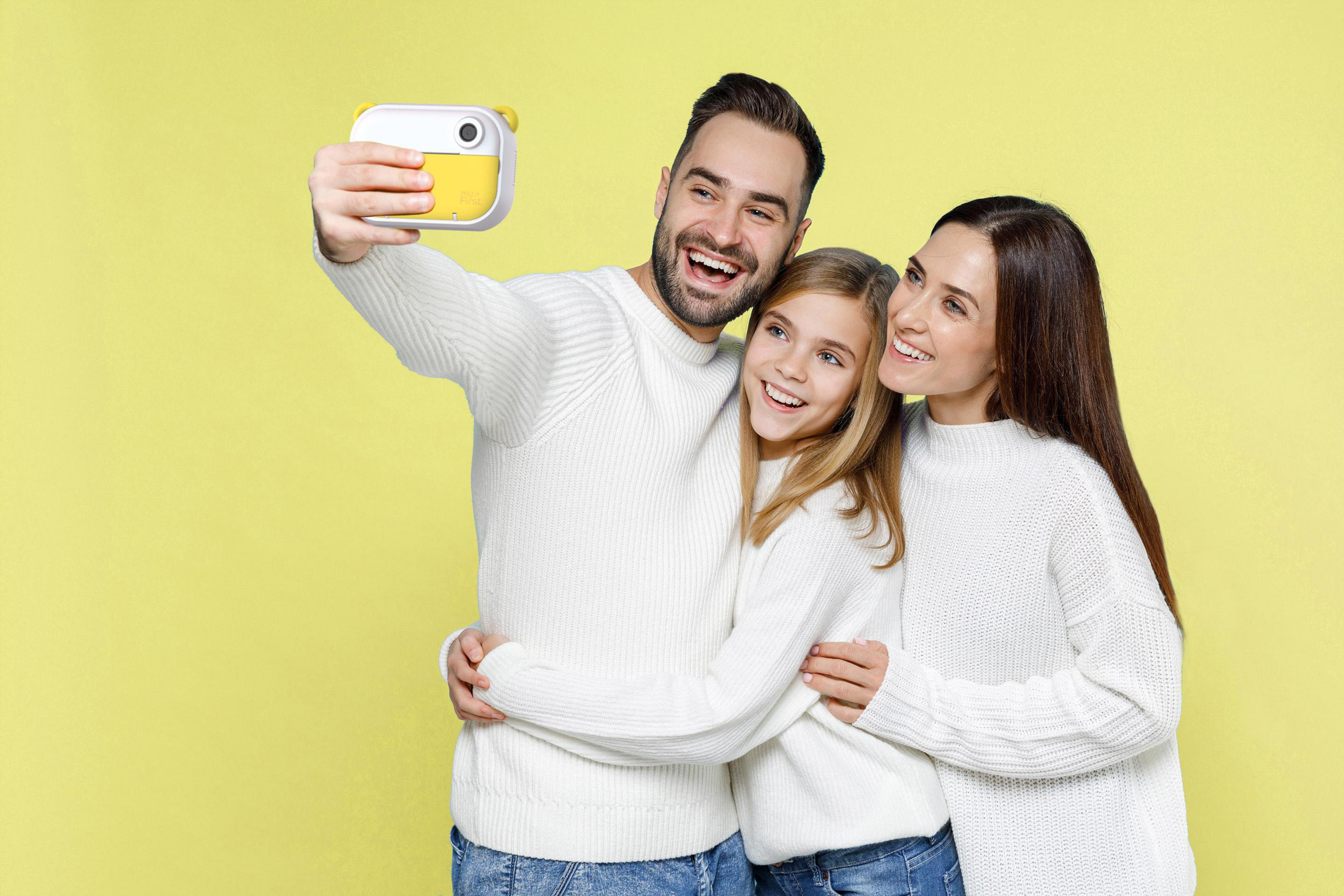 Eine Familie macht ein Selfie mit einer gelben Kamera.