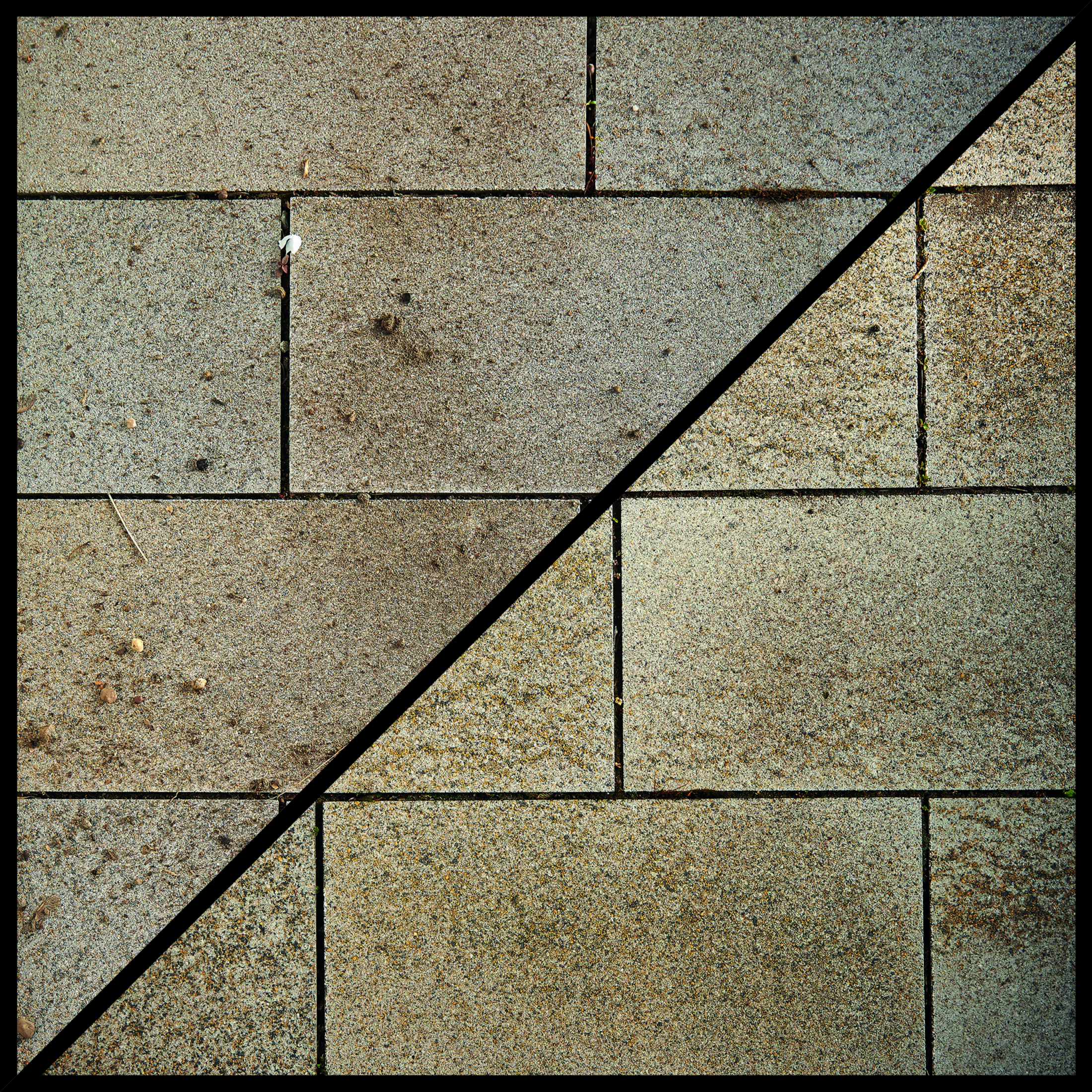 Grauer Pflastersteinweg mit einer schwarzen diagonalen Linie.