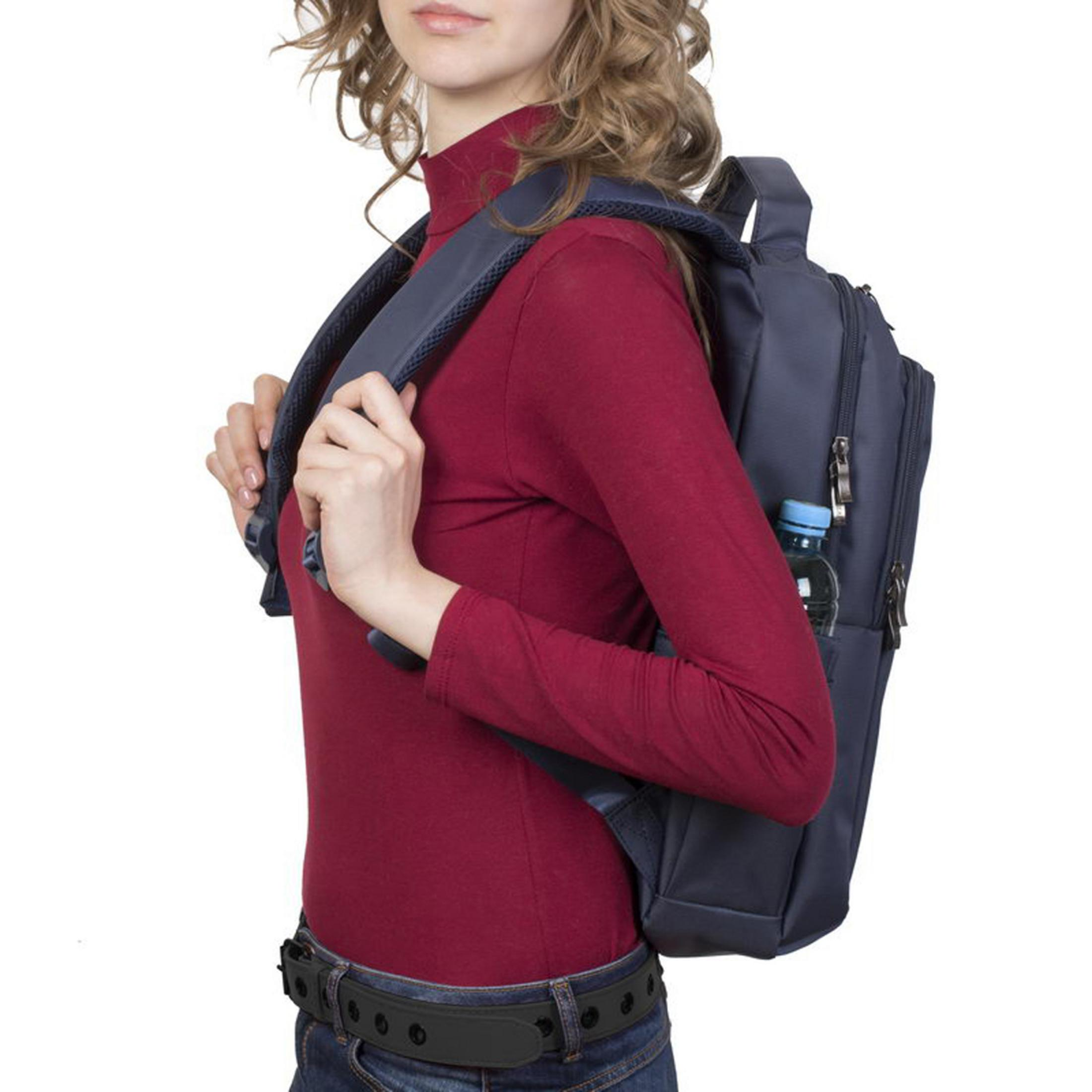 Una donna con capelli lunghi e mossi indossa uno zaino blu scuro e un dolcevita bordeaux.