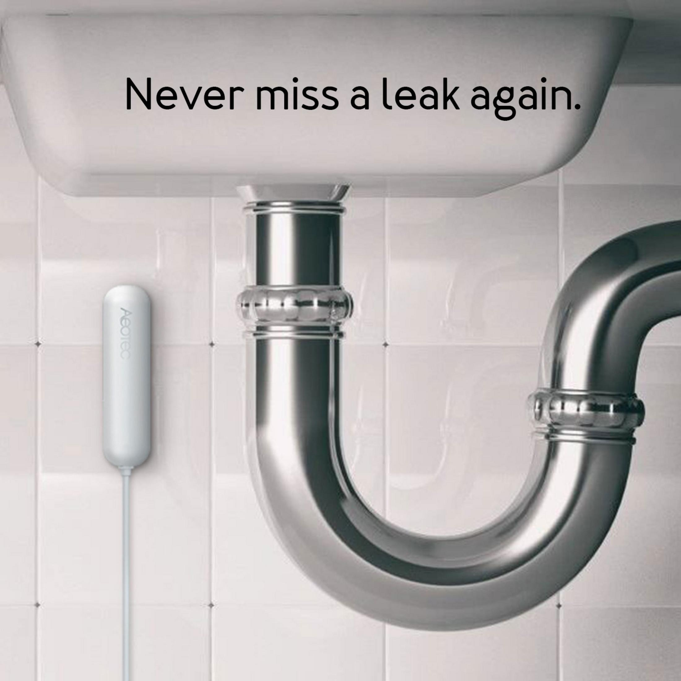 Ein weißer Sensor hängt neben einem glänzenden Siphon unter einem Waschbecken.