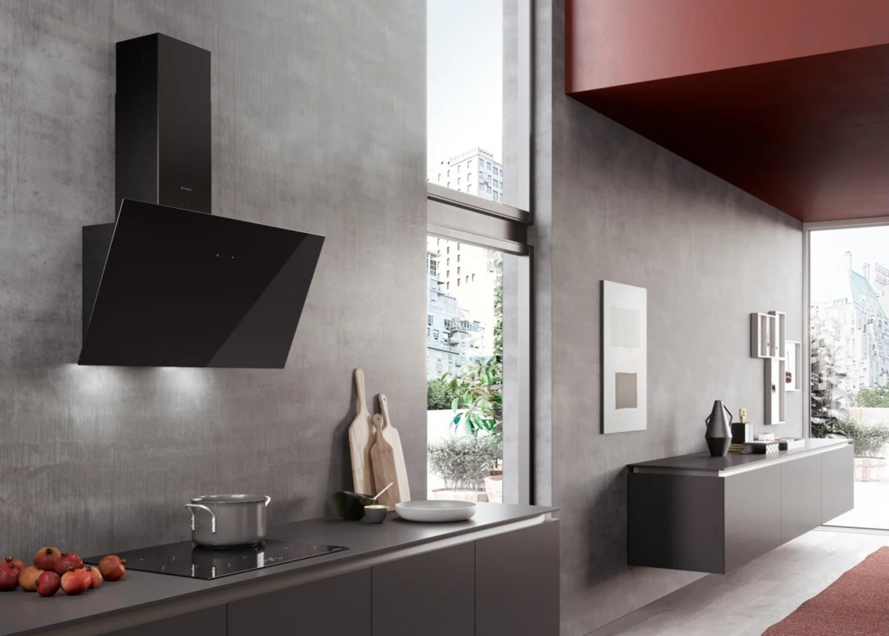 Cucina moderna con cappa nera, piano cottura a induzione e frutta sul bancone.