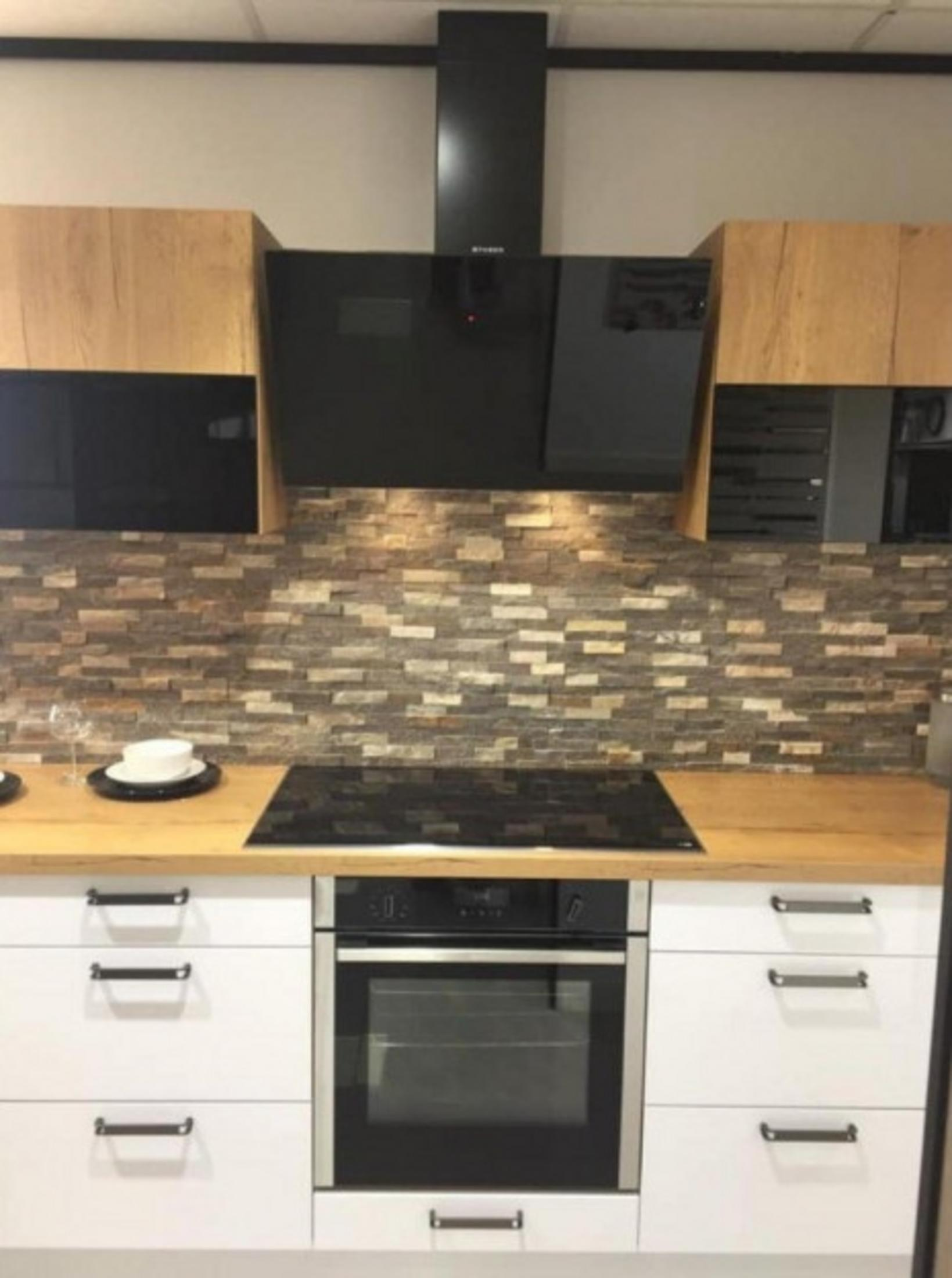 Cucina moderna con superfici in legno, paraschizzi in pietra, cappa nera e forno.
