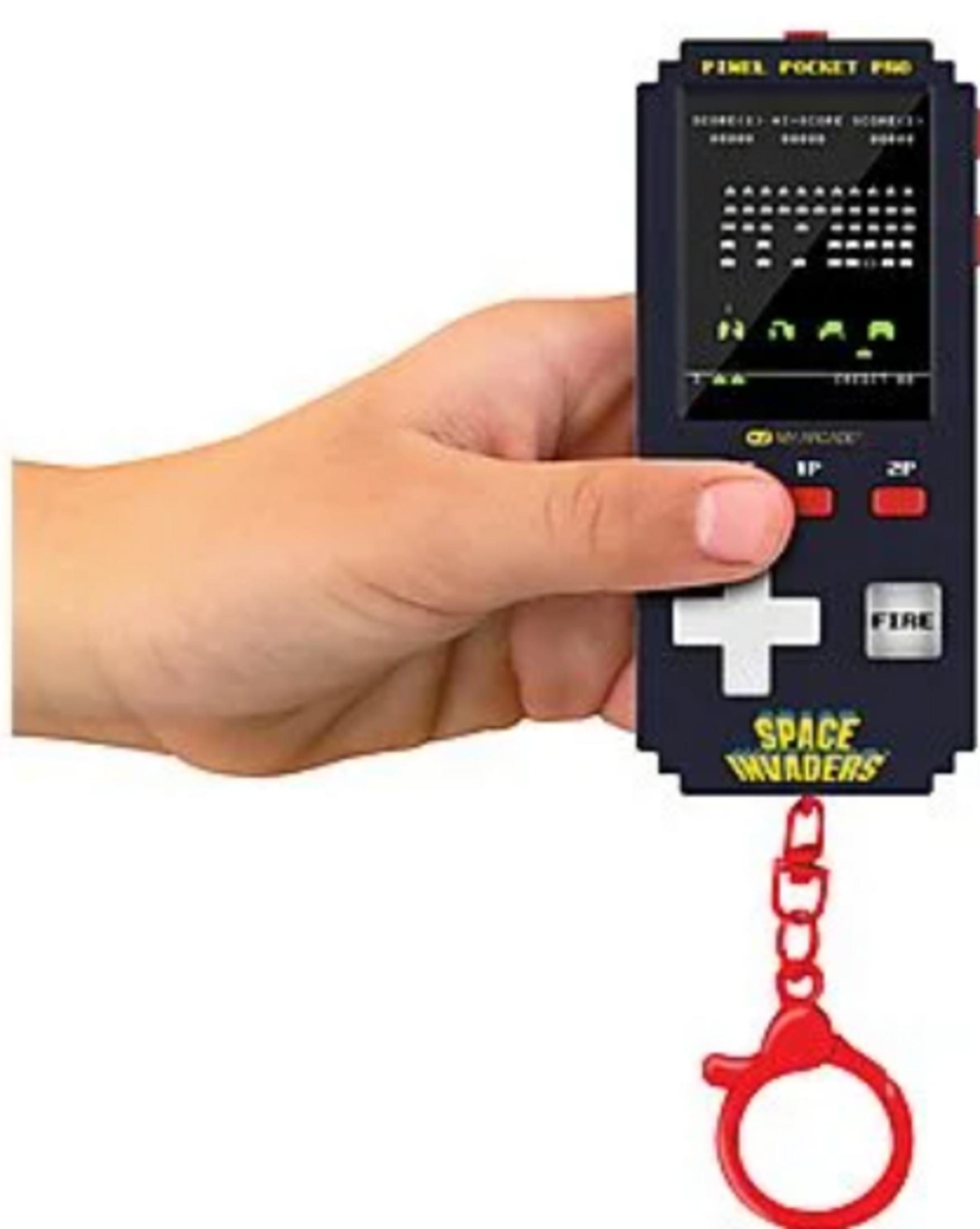 Una mano tiene un piccolo gioco portatile nero "Space Invaders" con un portachiavi rosso.