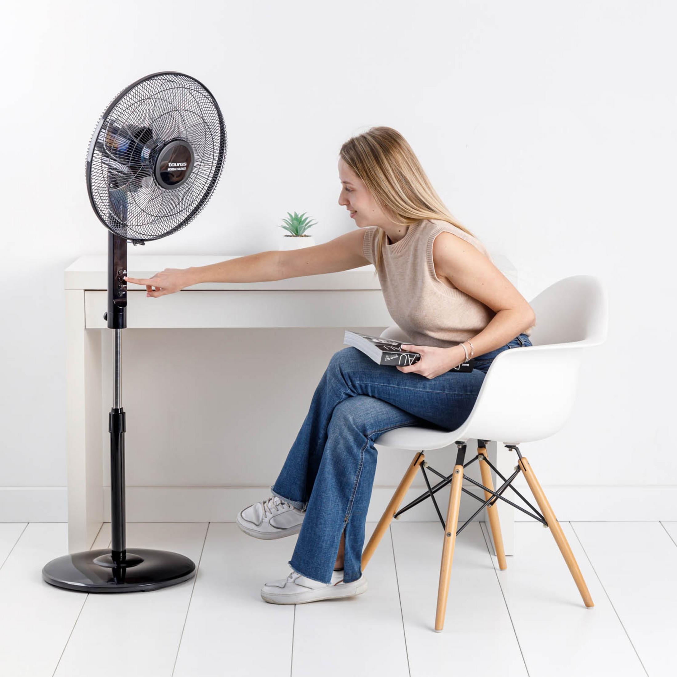 Una donna seduta su una sedia accende un ventilatore.