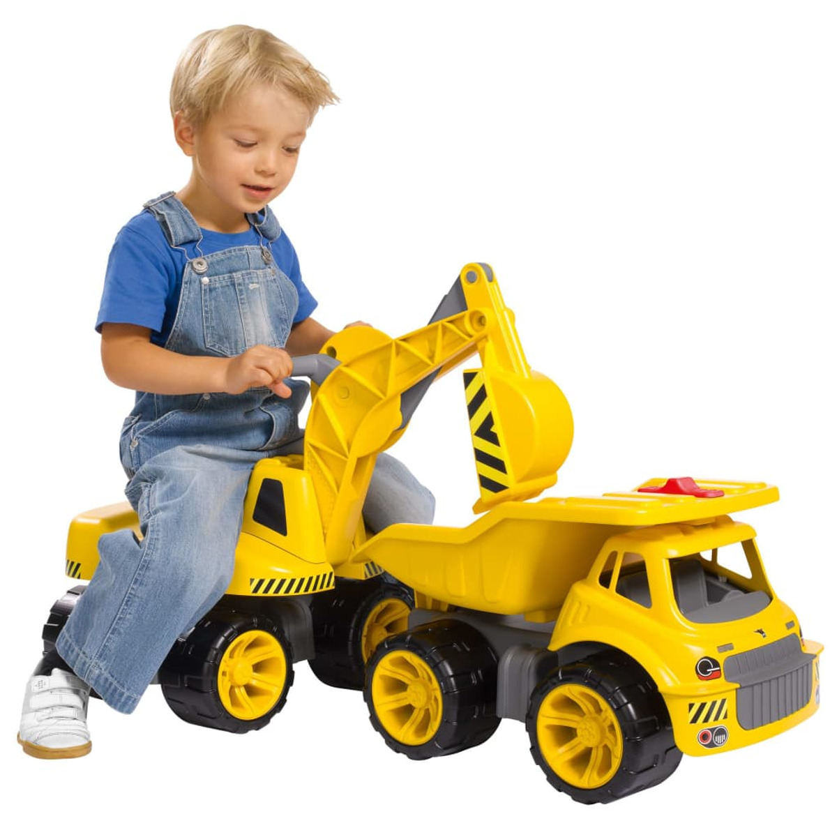 Ein kleiner Junge in Latzhose fährt auf einem gelben Bagger-LKW.