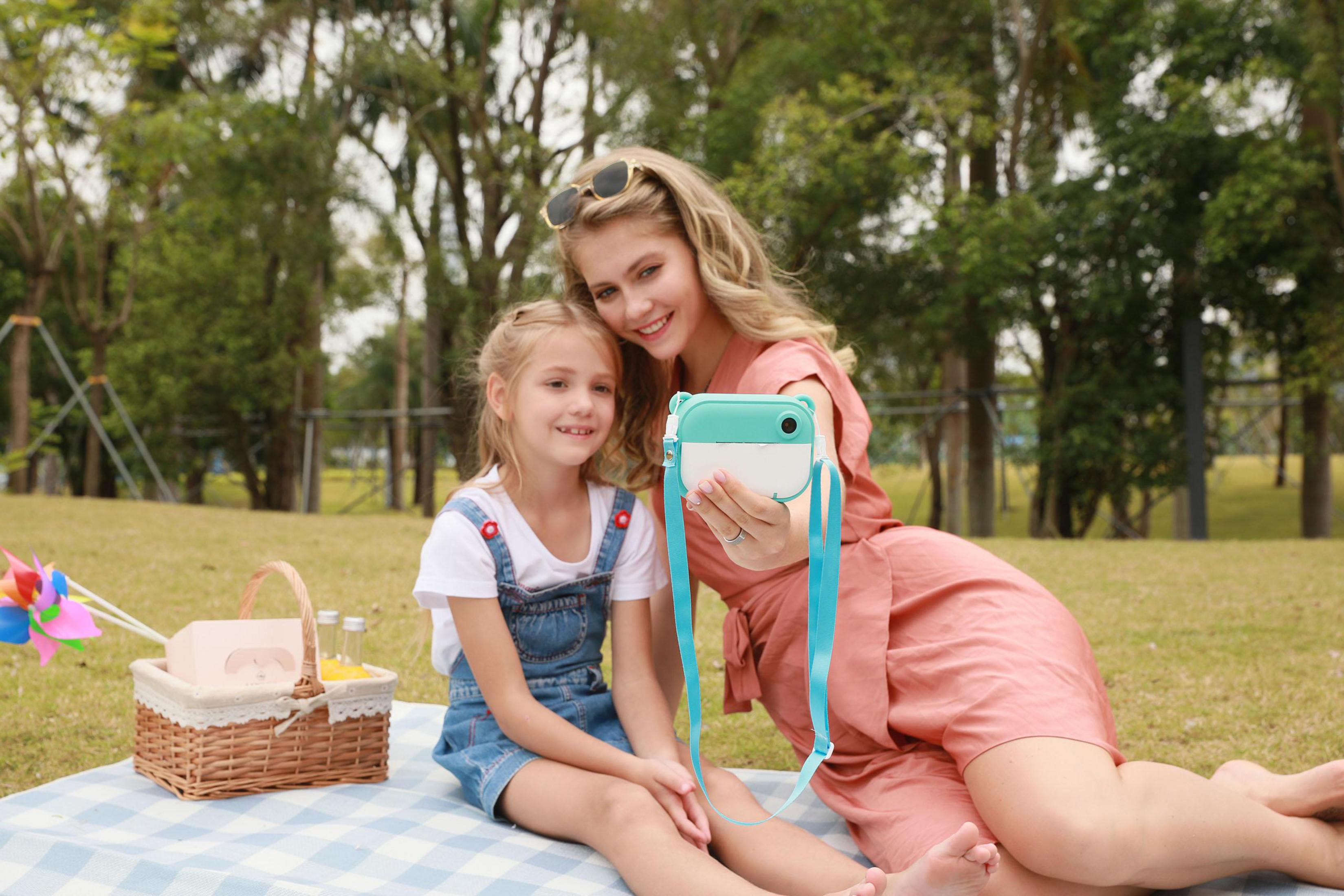 Mujer y niña haciendo un picnic en un parque con una cámara.