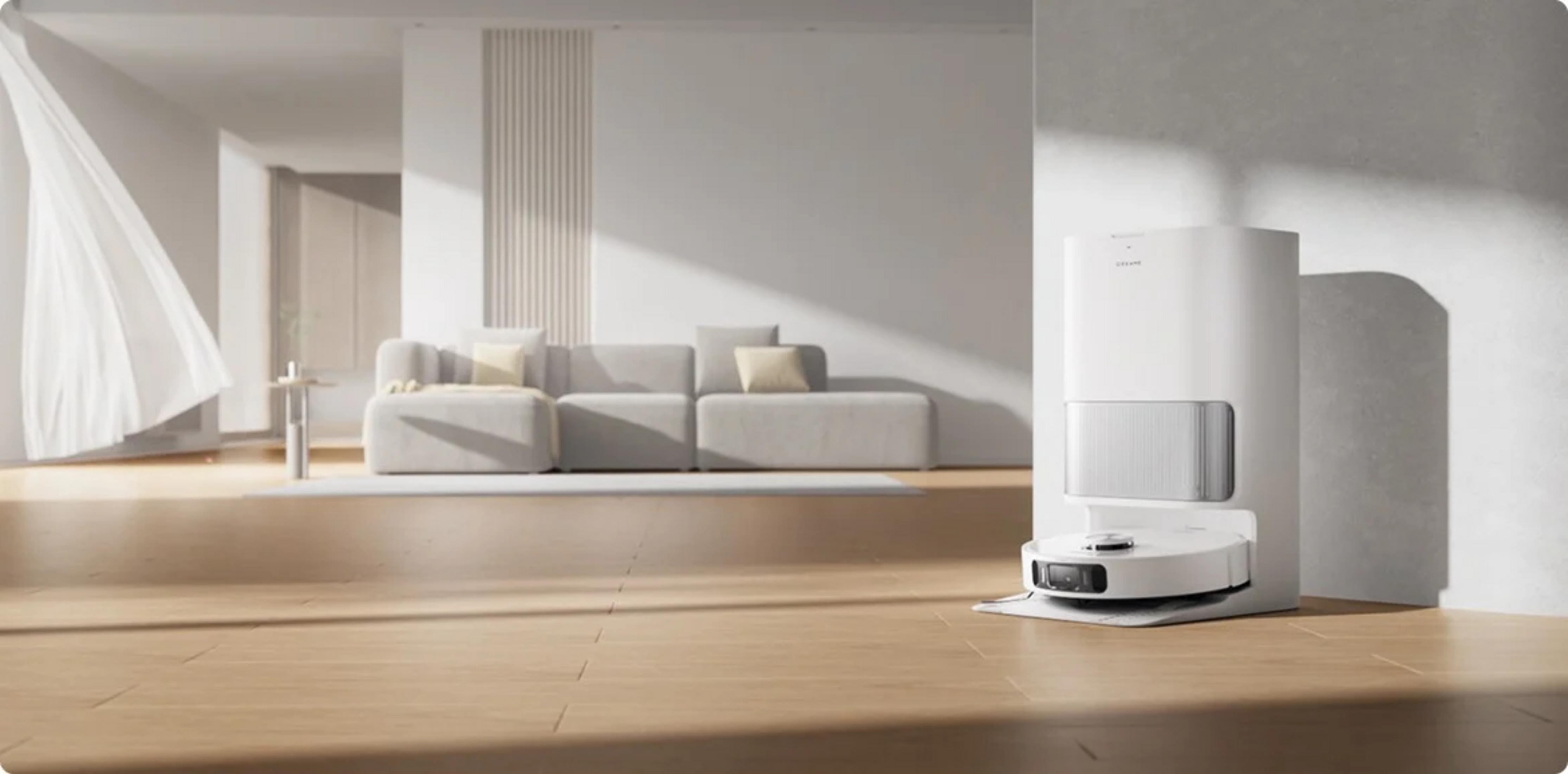 Un robot aspirapolvere bianco sulla sua base di ricarica in un soggiorno luminoso con divano.