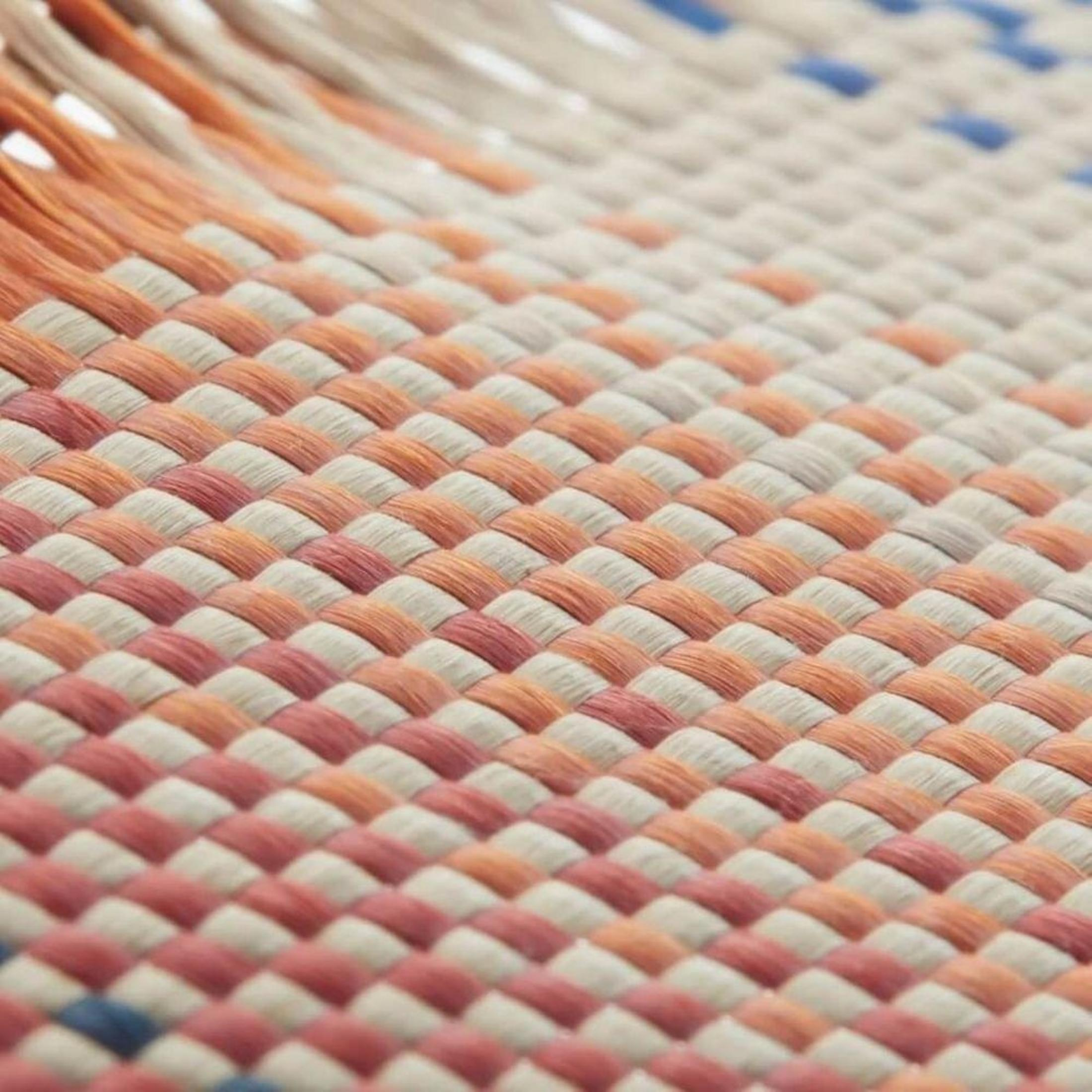 Geflochtenes Muster mit orangefarbenen, cremefarbenen und blauen Fäden.