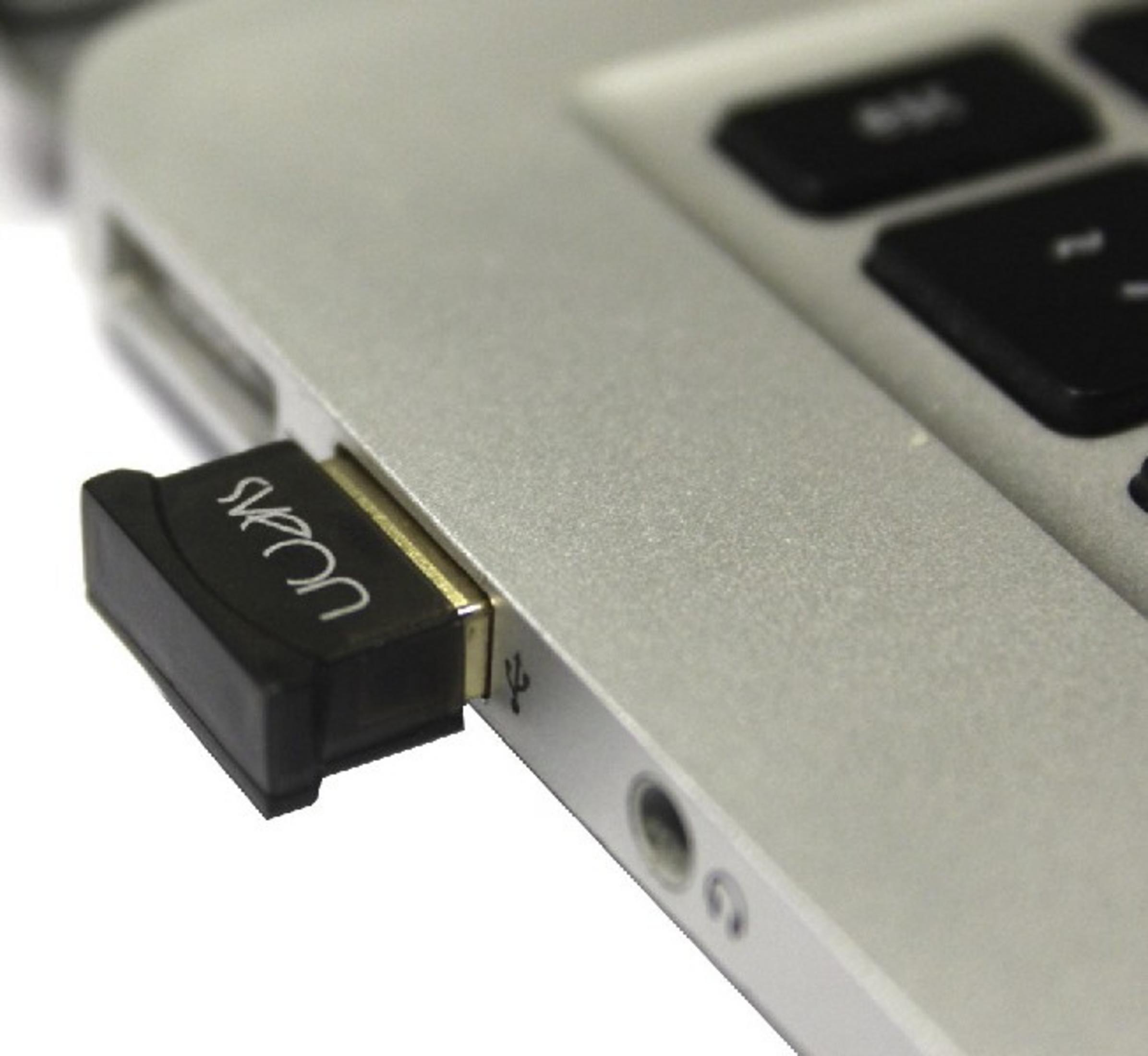 Un adaptador USB negro está enchufado en un portátil plateado.