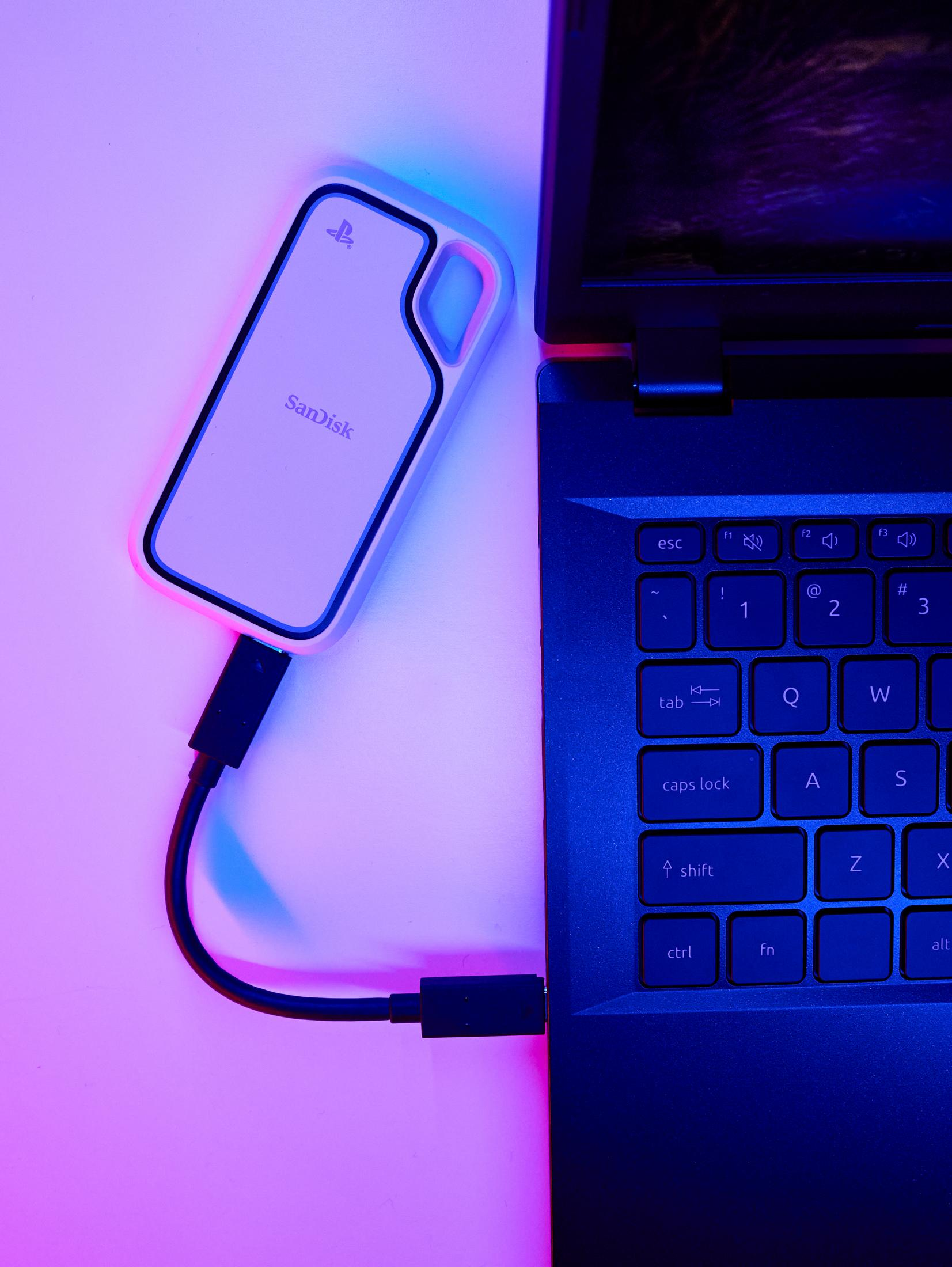 Un'unità SanDisk bianca è collegata a un laptop tramite un cavo nero.