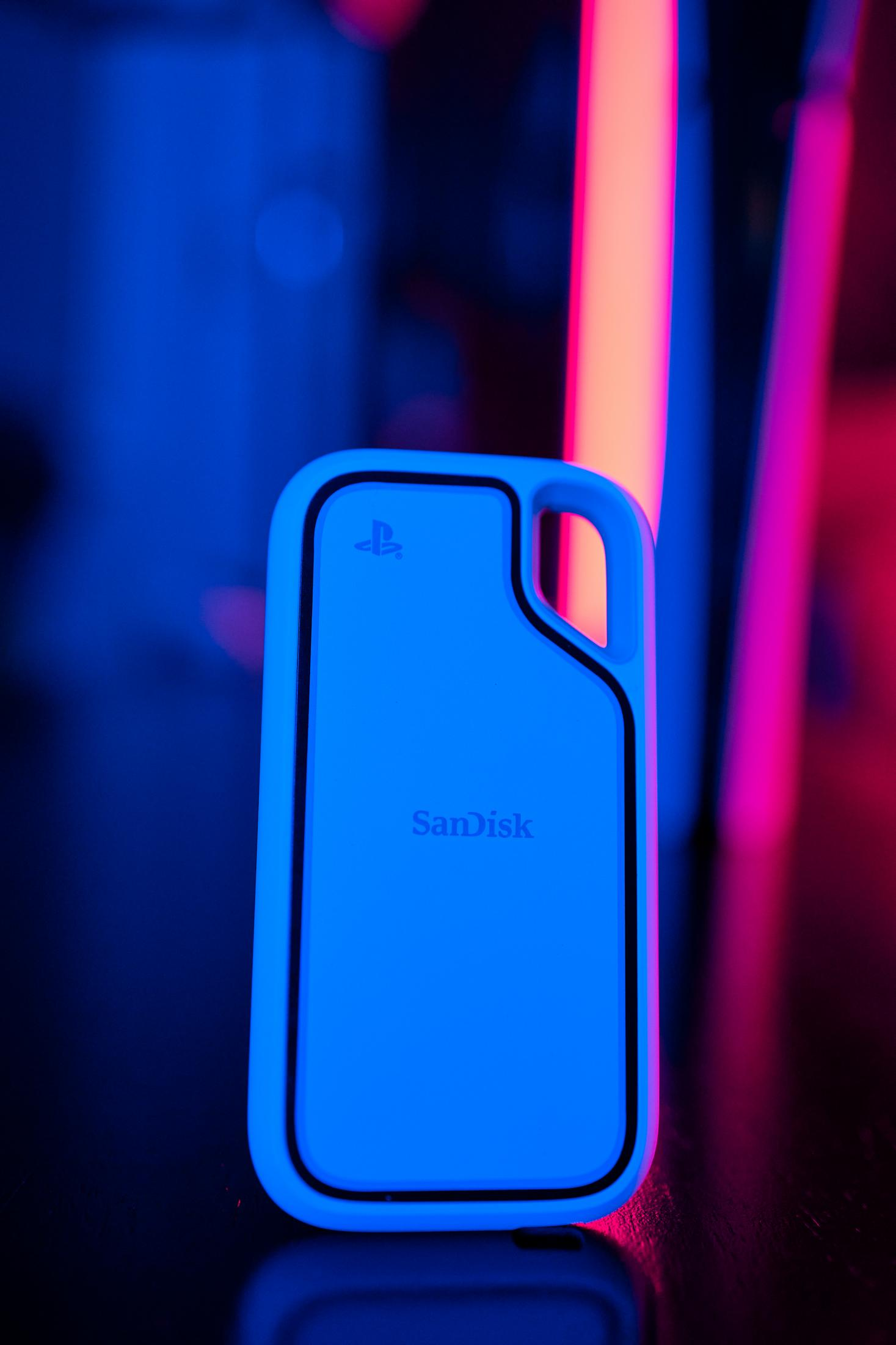 Un drive SanDisk blu con logo PlayStation illuminato da luci al neon.